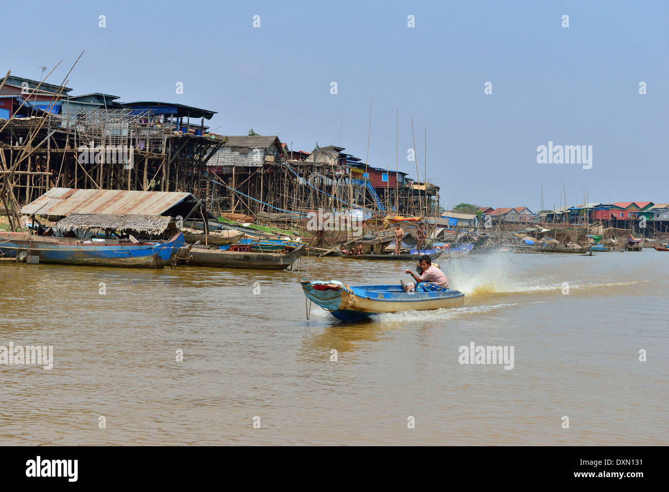Bateau à grande vitesse à longue queue qui ferriait les produits le long de la rivière avec des maisons sur pilotis sur le rivage jusqu'au lac Tonle SAP, au Cambodge, en Asie du Sud-est Banque D'Images