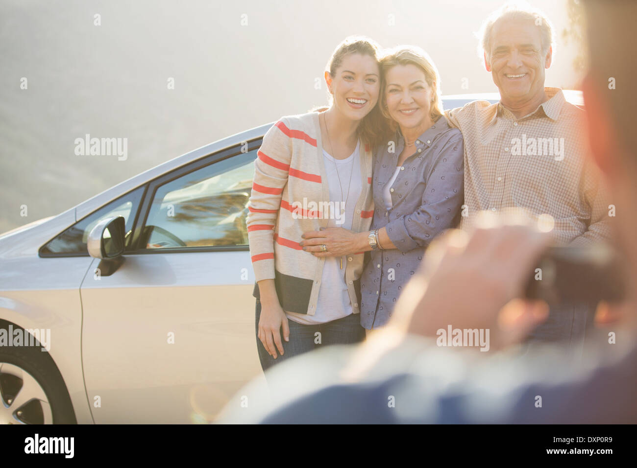 Man photographing family outside car Banque D'Images