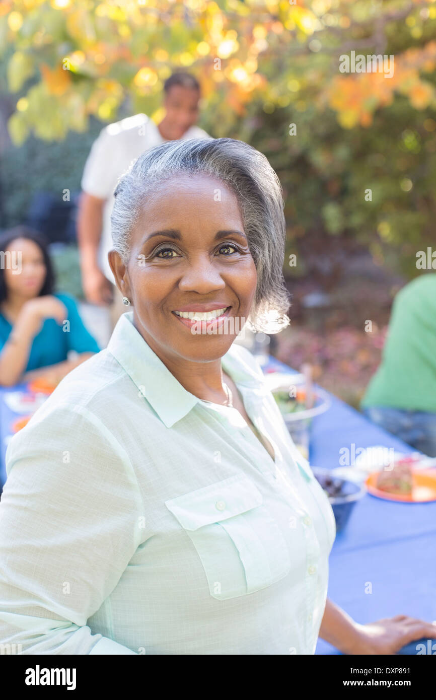 Close up portrait of smiling senior woman on patio avec la famille en arrière-plan Banque D'Images