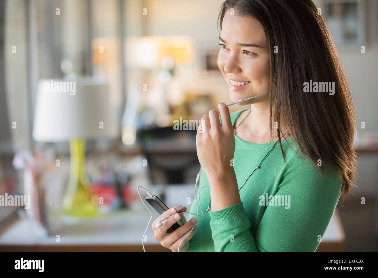 Smiling businesswoman using dispositif mains libres avec cell phone in office Banque D'Images
