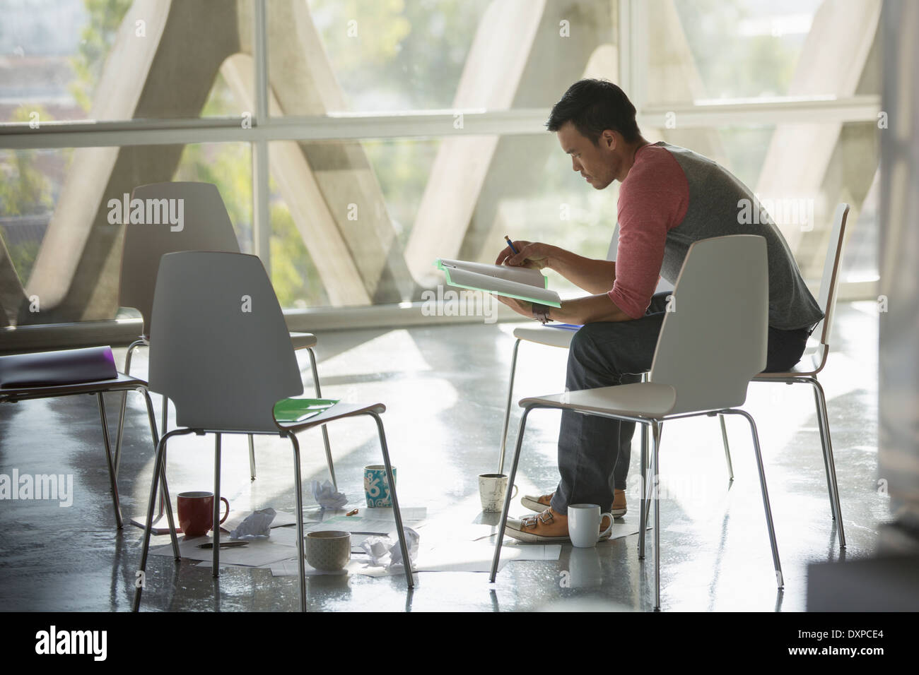 Businessman reviewing paperwork au cercle de chaises Banque D'Images