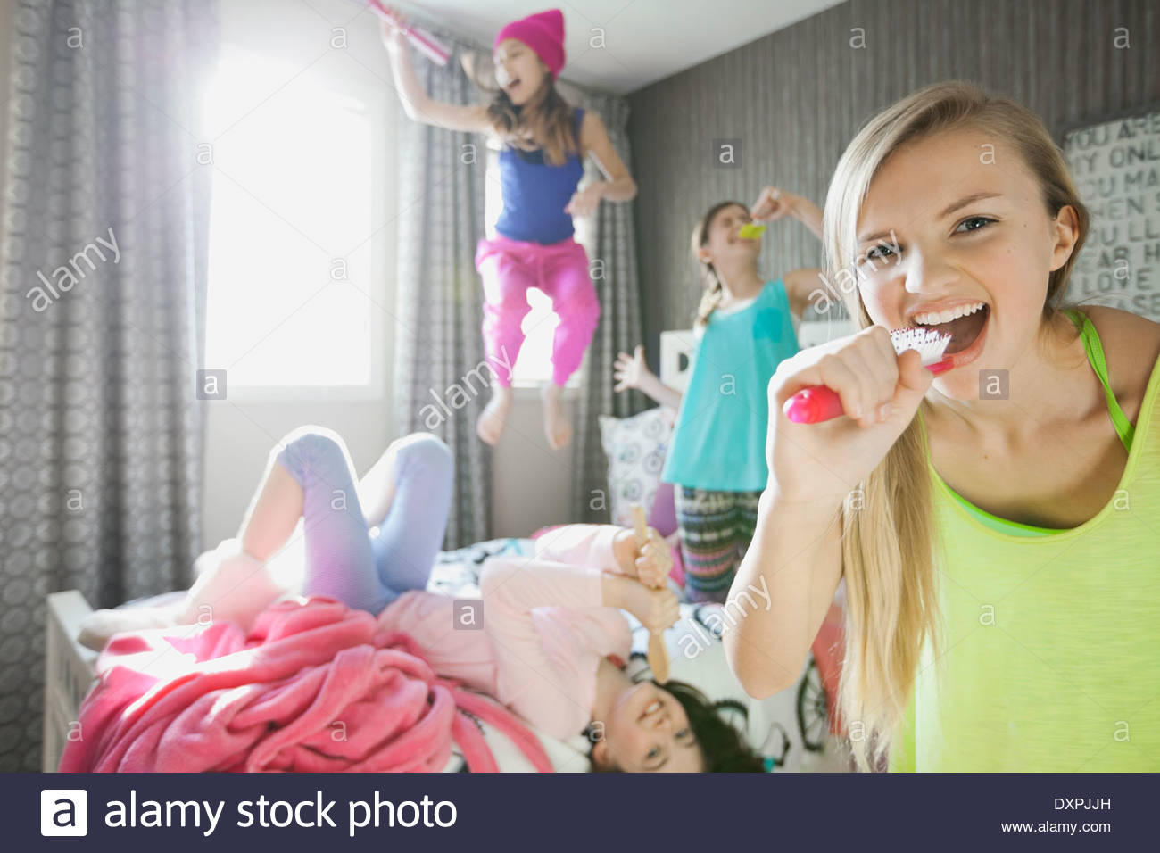 Girl singing into hairbrush at slumber party Banque D'Images