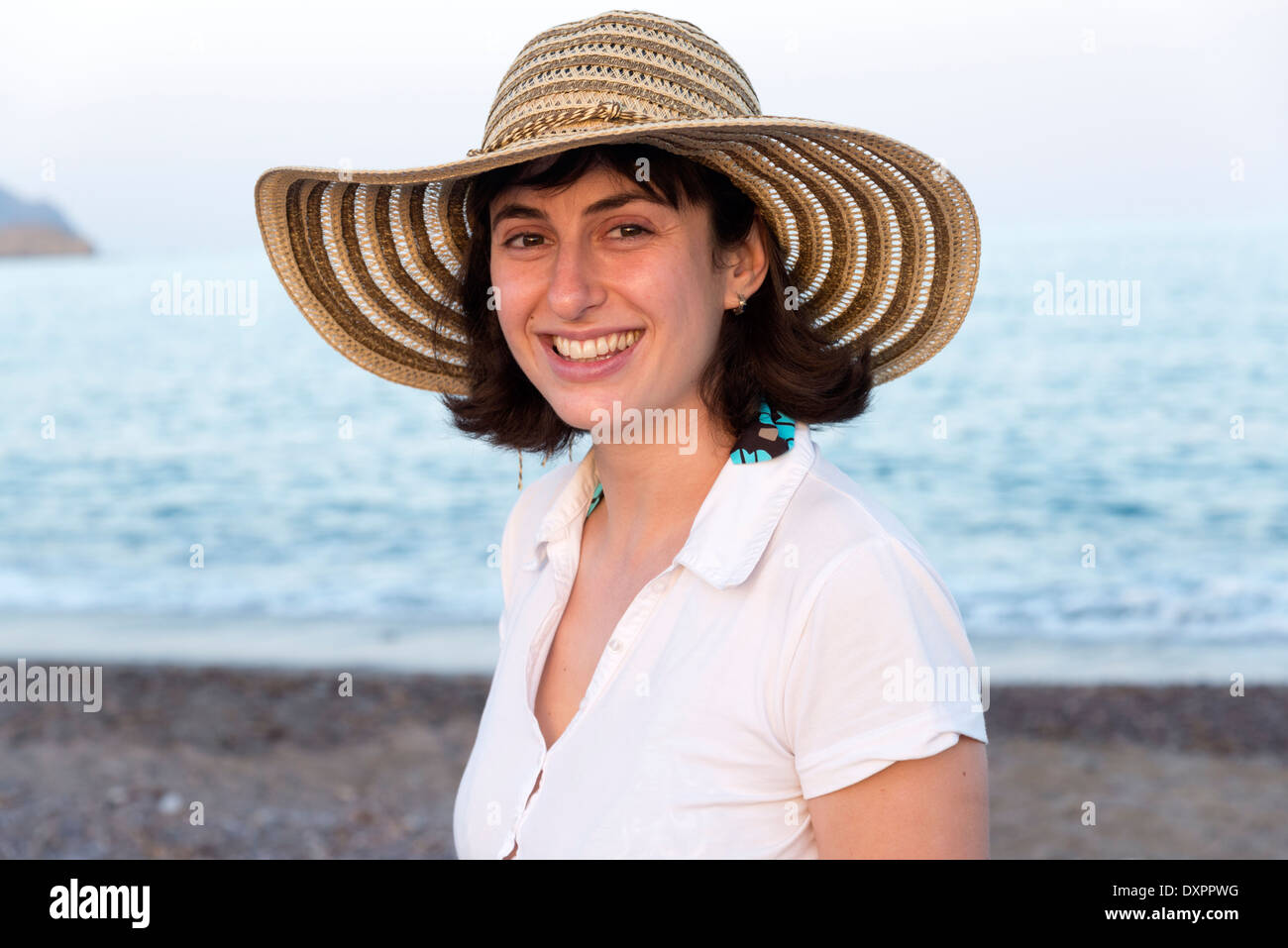 Young woman wearing straw hat à côté de la mer Banque D'Images