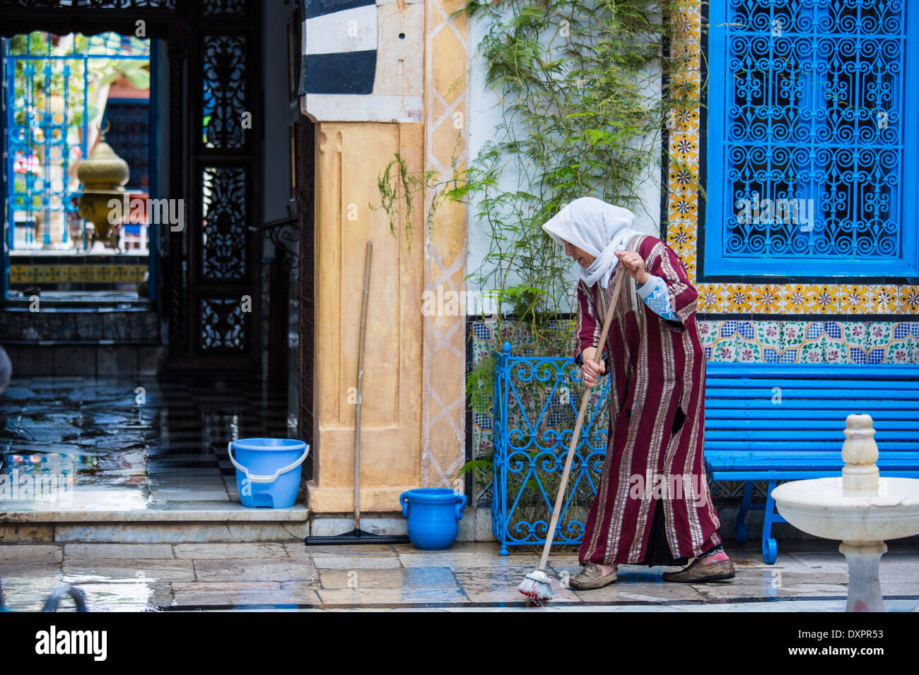 Woman sweeping un étage de Sidi Bou Saïd, Tunisie Banque D'Images