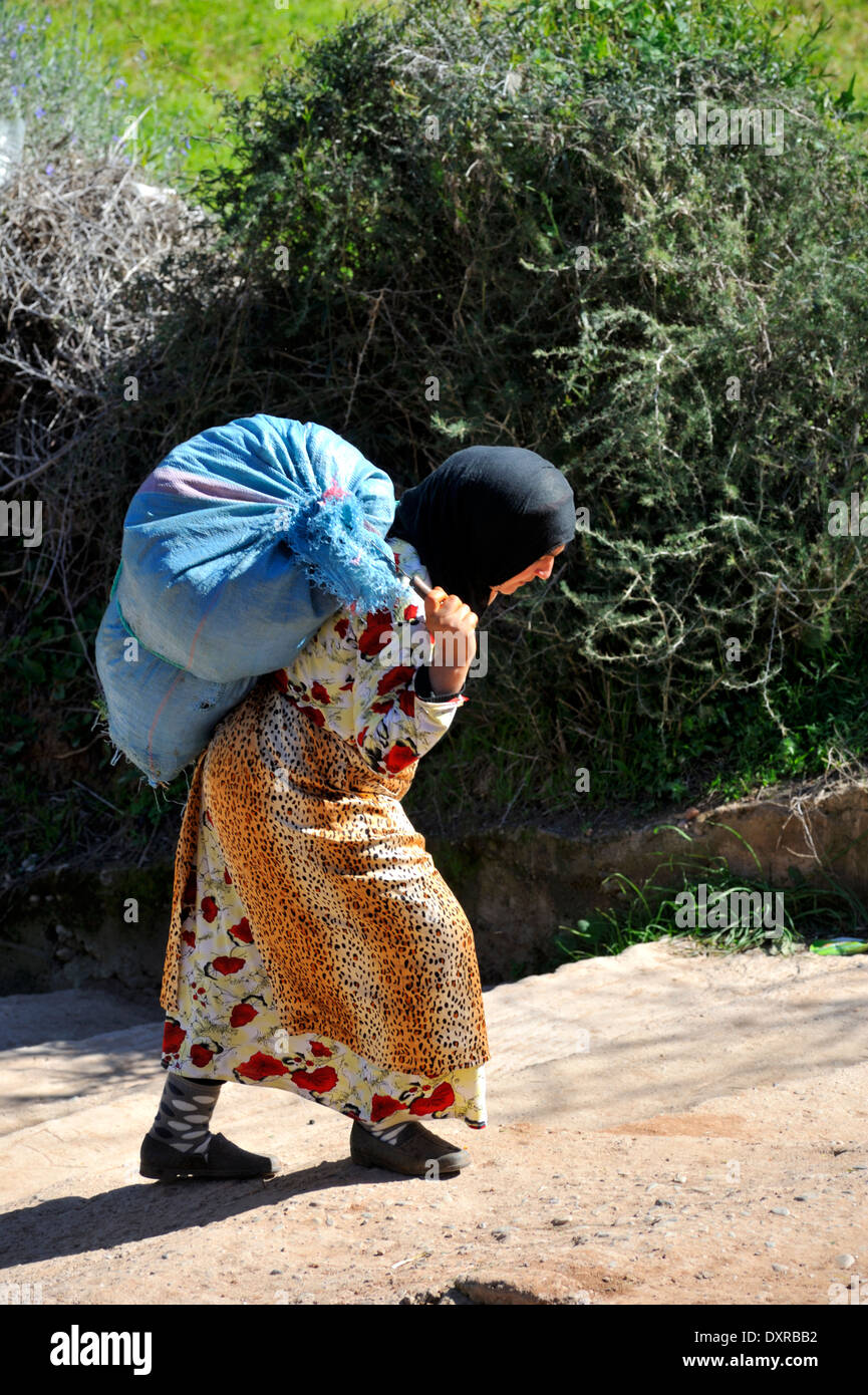 Femme Berbère marocain traditionnel dans une tenue colorée transportant un  grand sac de nourriture pour animaux Photo Stock - Alamy