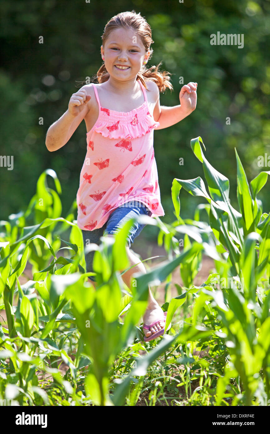 Jeune fille courir à travers un champ agricole Banque D'Images