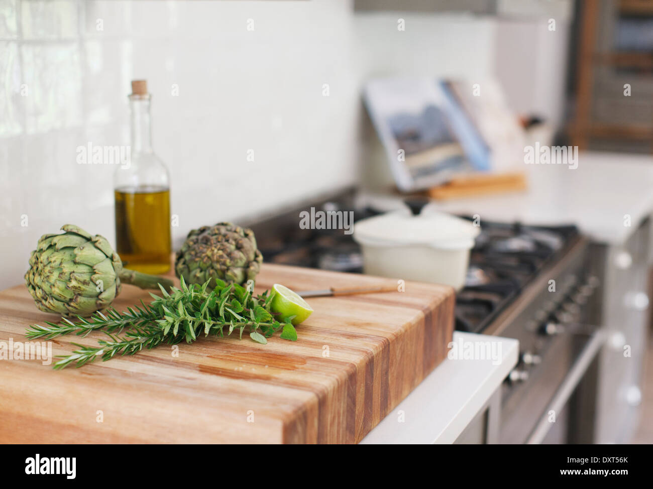 Artichaut, romarin, huile d'olive et citron vert on cutting board Banque D'Images