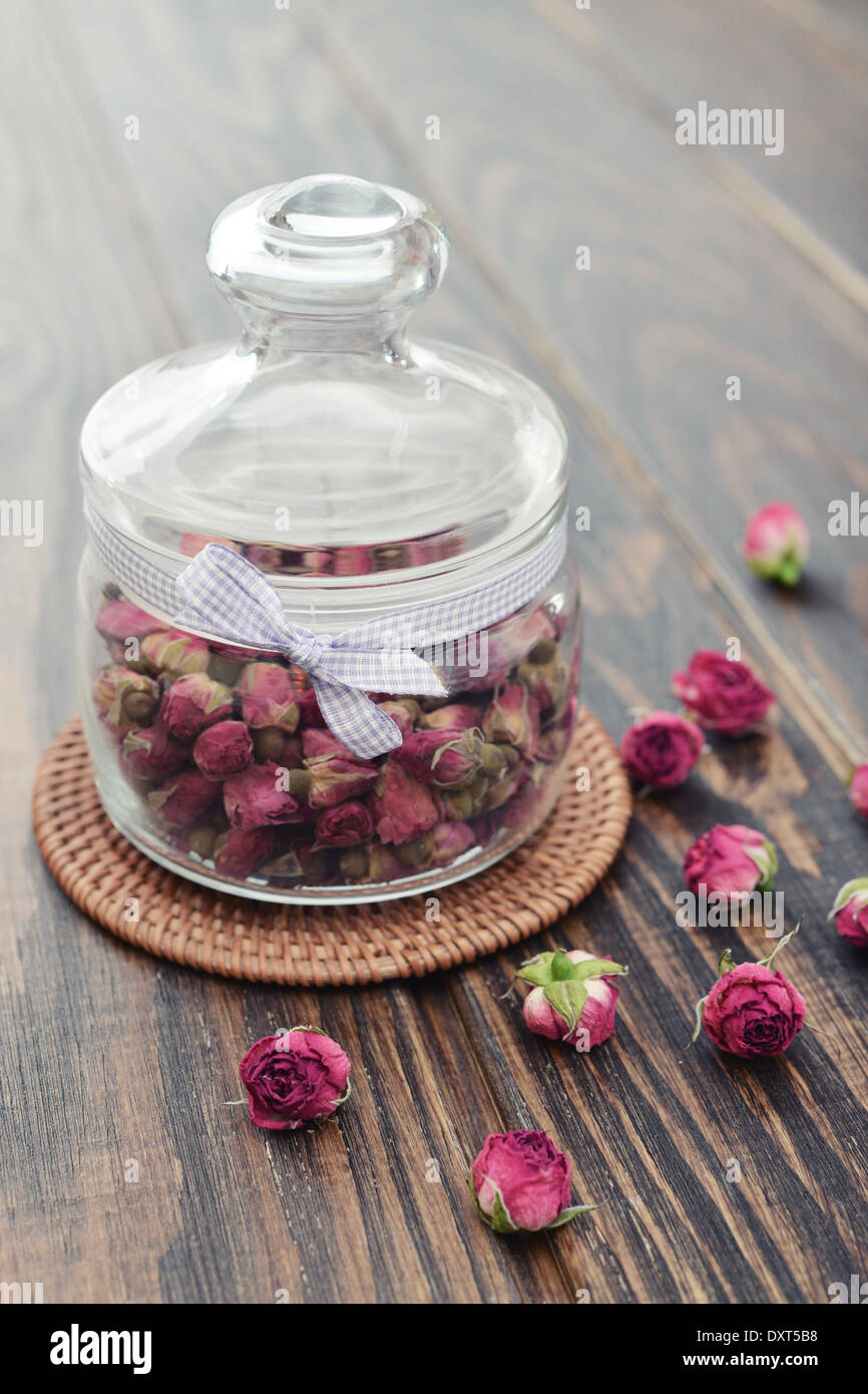 Plateau rose fleurs en pot de verre sur fond de bois Banque D'Images