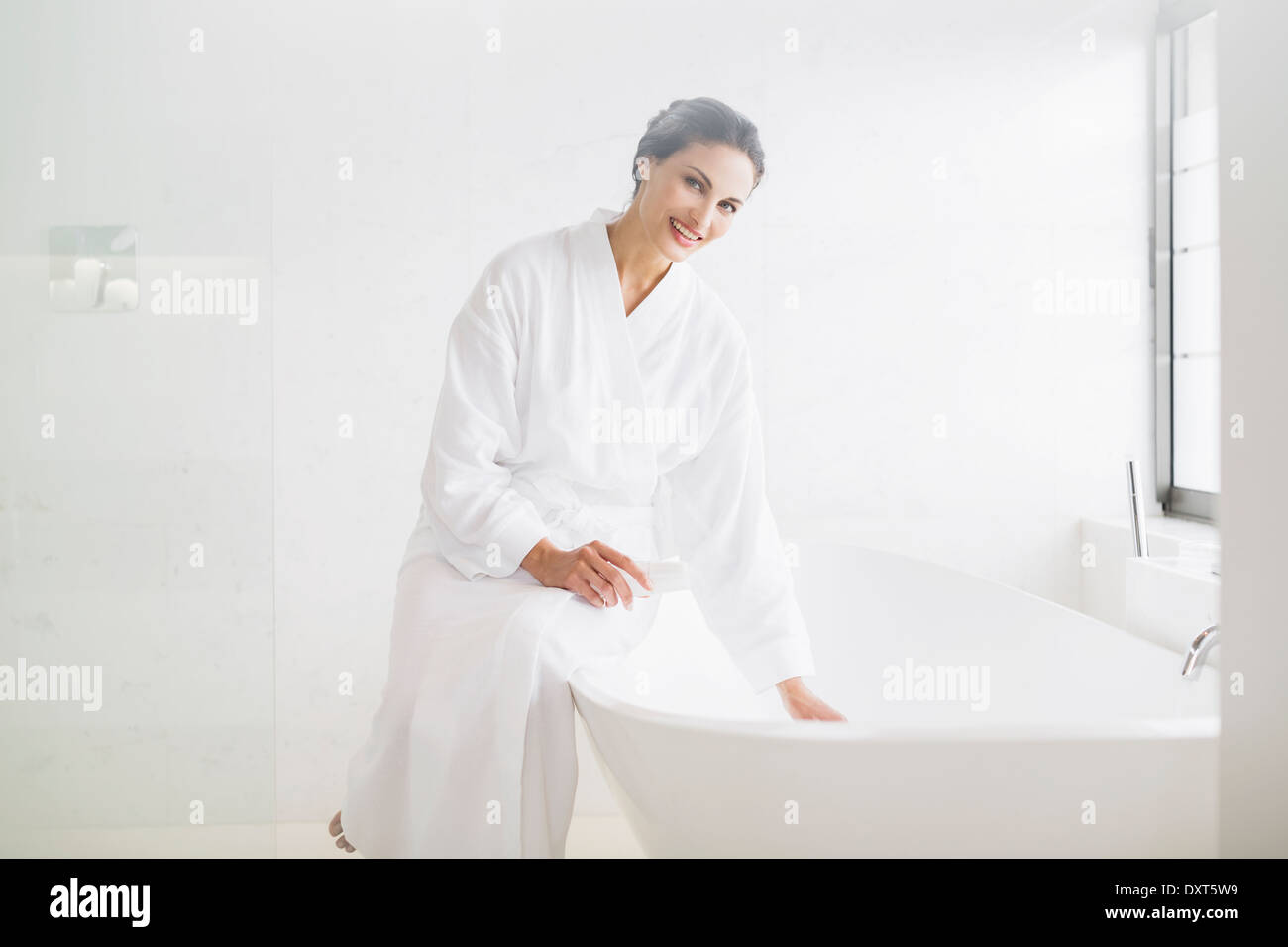 Portrait of smiling woman in bathrobe préparation baignoire Banque D'Images