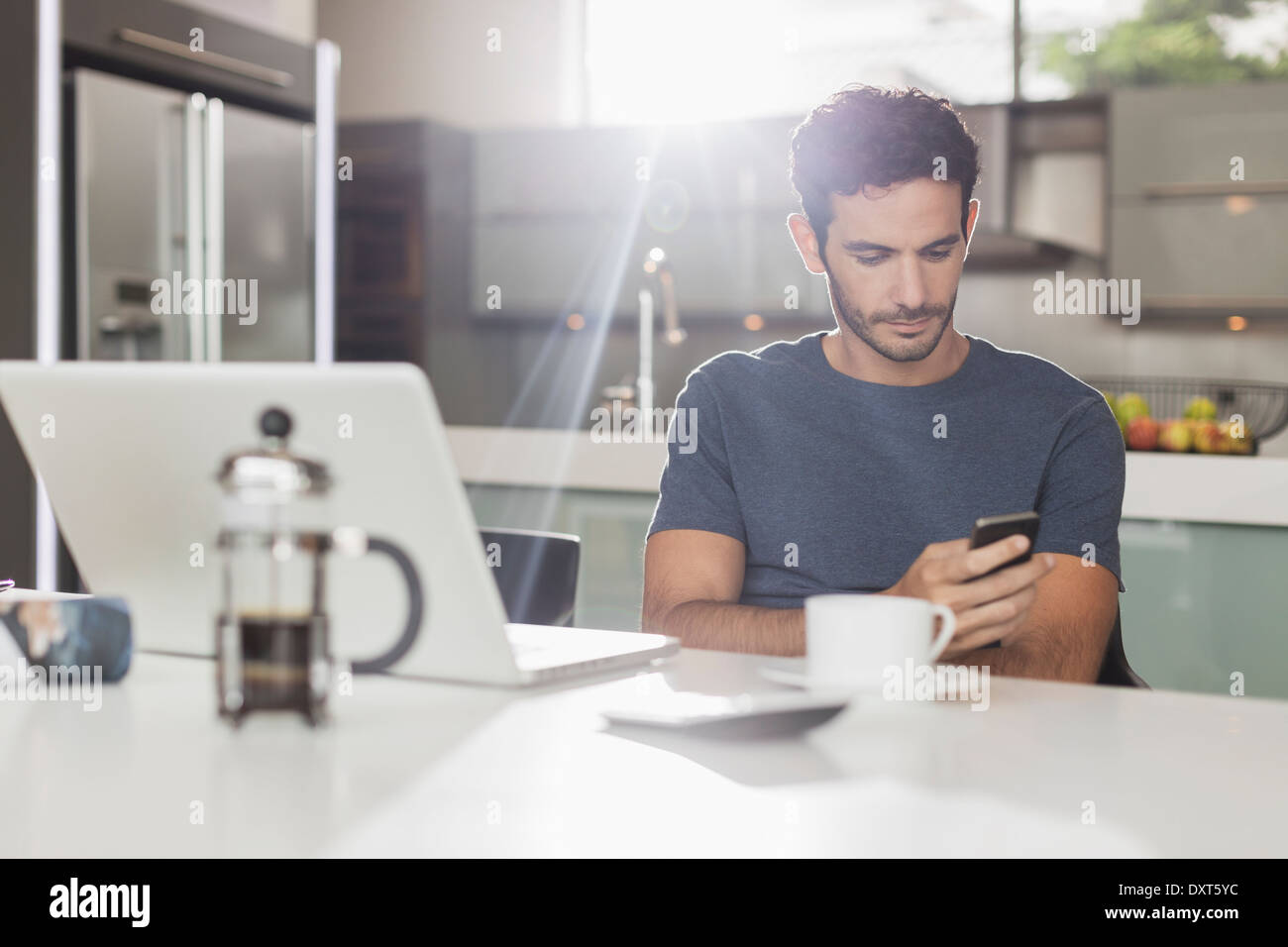 Man texting with cell phone at table de cuisine Banque D'Images