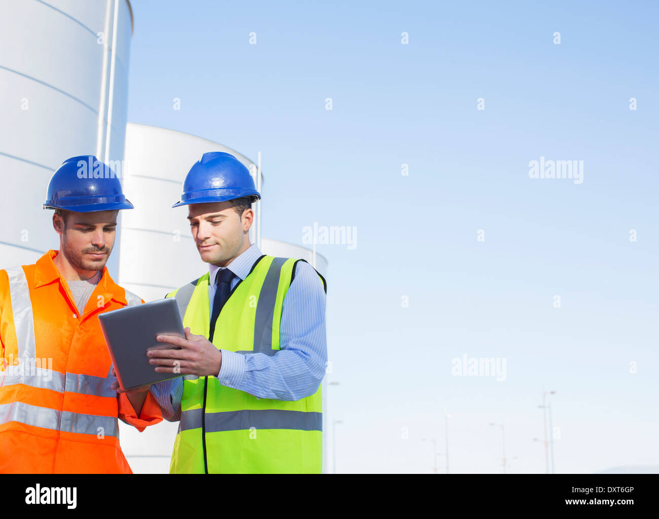 Les travailleurs utilisant tablette numérique près de tours de stockage d'ensilage Banque D'Images