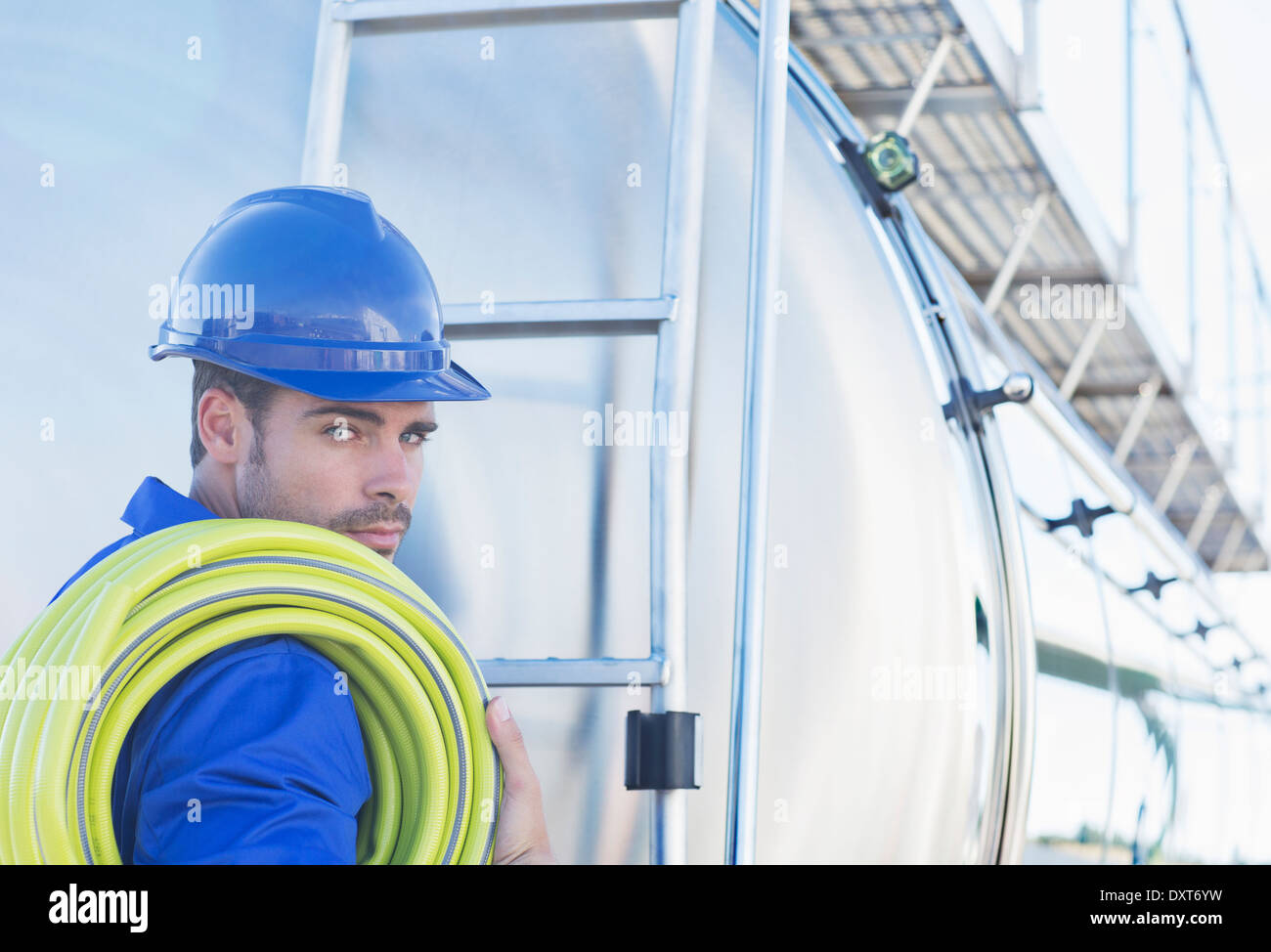 Portrait de travailleur sérieux avec le tuyau à l'arrière du camion-citerne de lait en acier inoxydable Banque D'Images