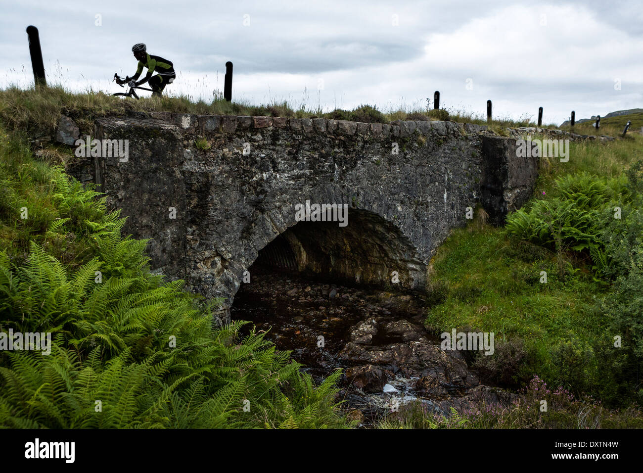 Un cycliste traverse un pont sur la route la plus longue ascension en Lochcarron, Ecosse Banque D'Images
