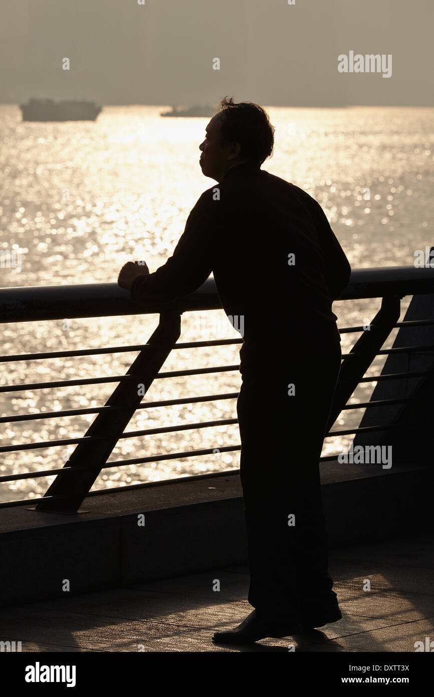 Un homme a fait des silhouettes contre le soleil levant, faisant des exercices tôt le matin sur le Bund, au bord de la rivière, à Shanghai, en Chine. Banque D'Images
