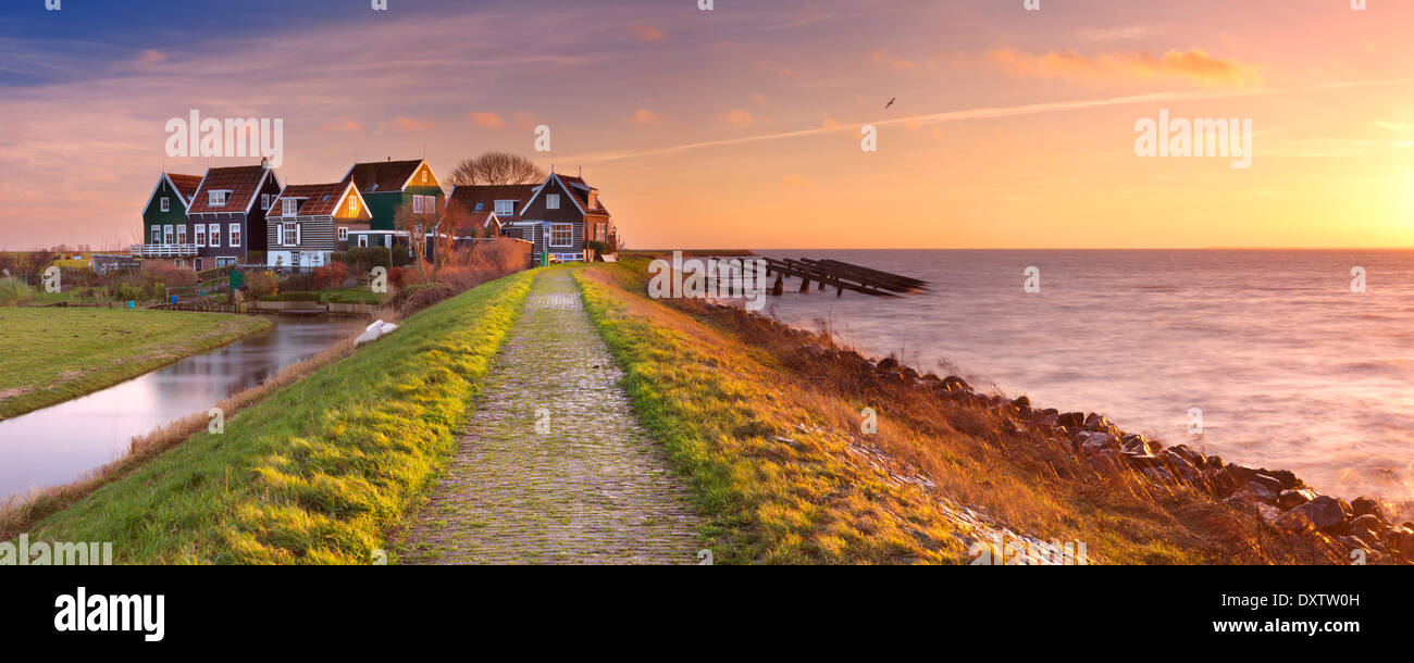 Petit village derrière une digue, photographié sur l'île de Marken dans les Pays-Bas au lever du soleil Banque D'Images