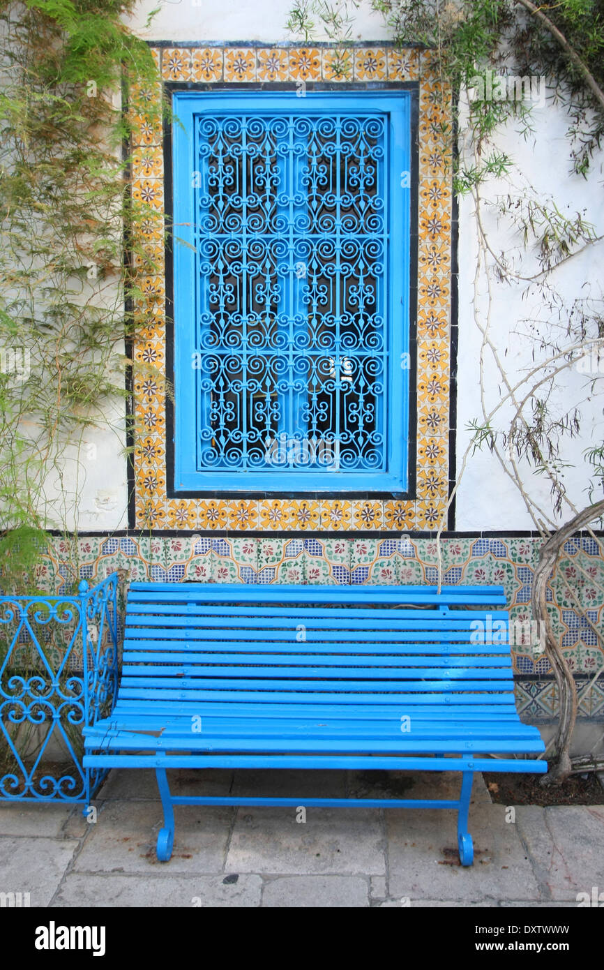 Banc bleu et fenêtre dans la cour d'une maison typique de Sidi Bou Saïd, Tunisie. Banque D'Images