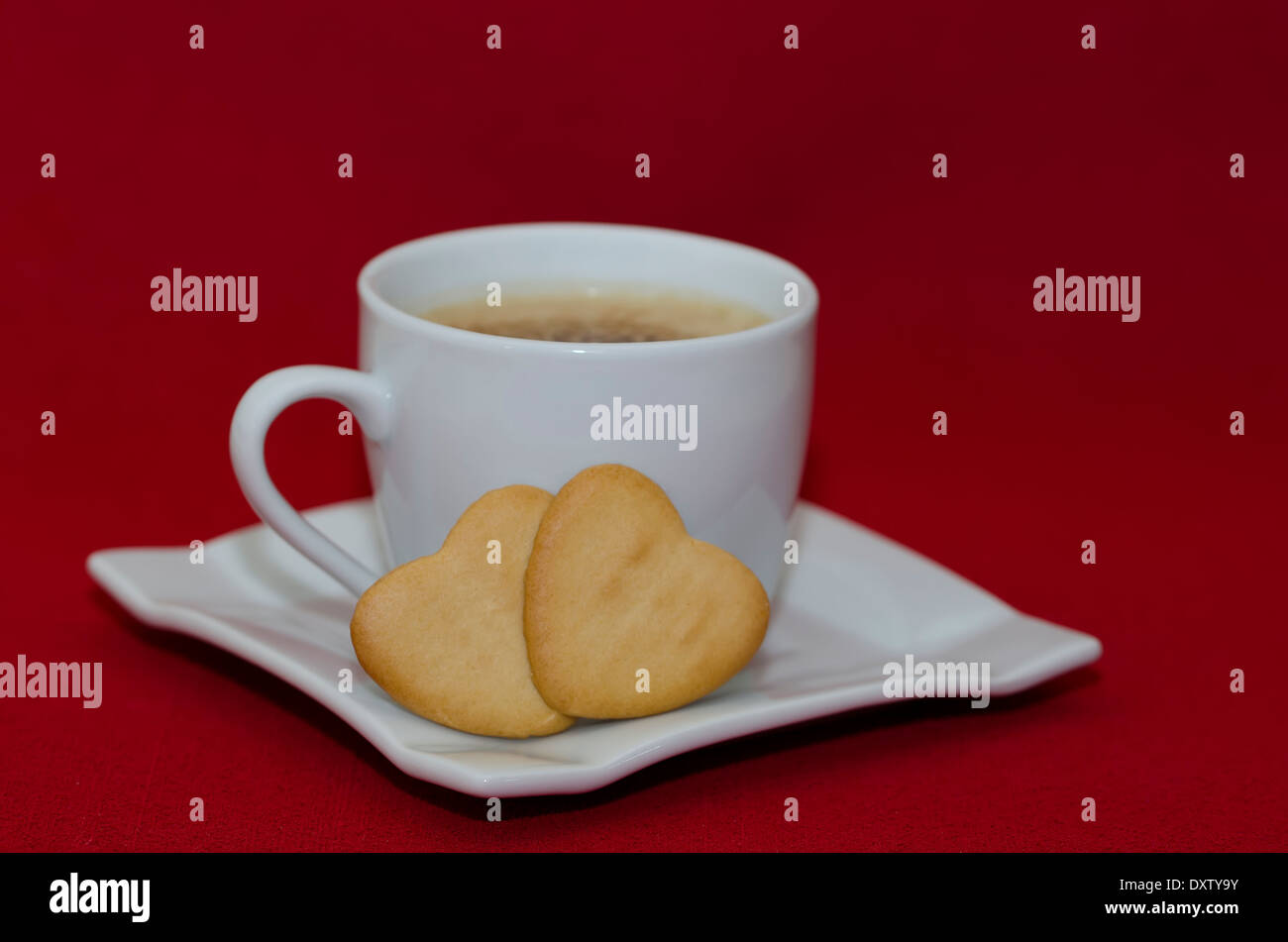 Tasse à café et deux cookies en forme de coeur sur fond rouge avec l'exemplaire de l'espace. Banque D'Images