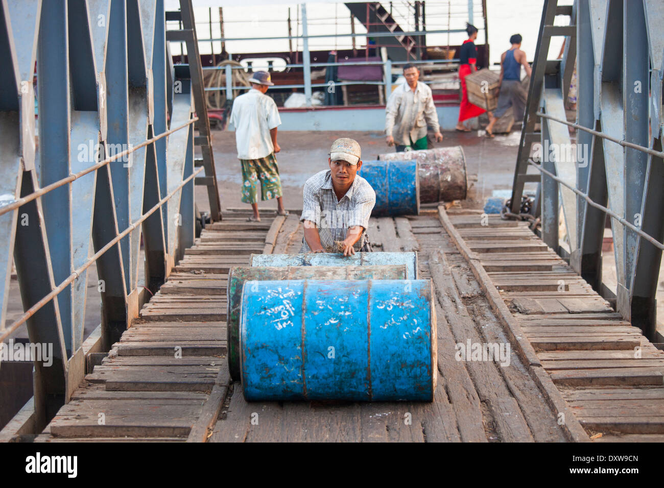 Poussant un baril de carburant vide au port de Yangon, Myanmar Banque D'Images