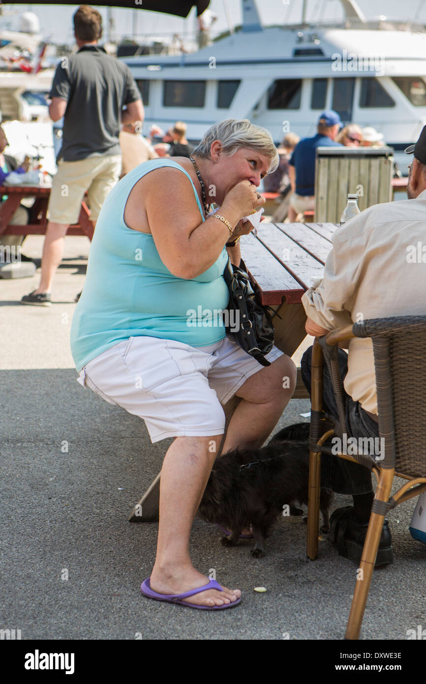 Femme assise sur un banc et manger un hamburger Banque D'Images