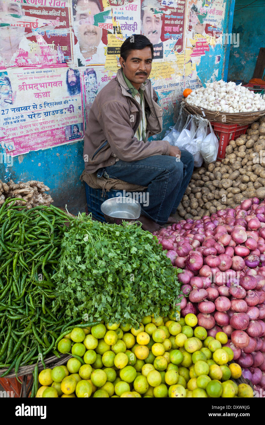 L'Inde, Dehradun. L'homme la vente de pommes de terre, les oignons, les oranges, les poivrons, le gingembre et l'Ail, tout en écoutant de la musique sur les écouteurs. Banque D'Images