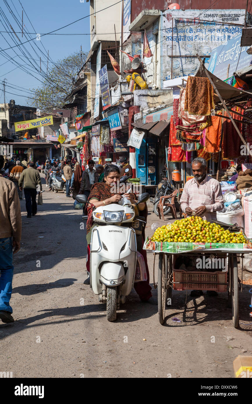 L'Inde, Dehradun. Femme sur moto acheter des fruits à un vendeur de rue. Banque D'Images