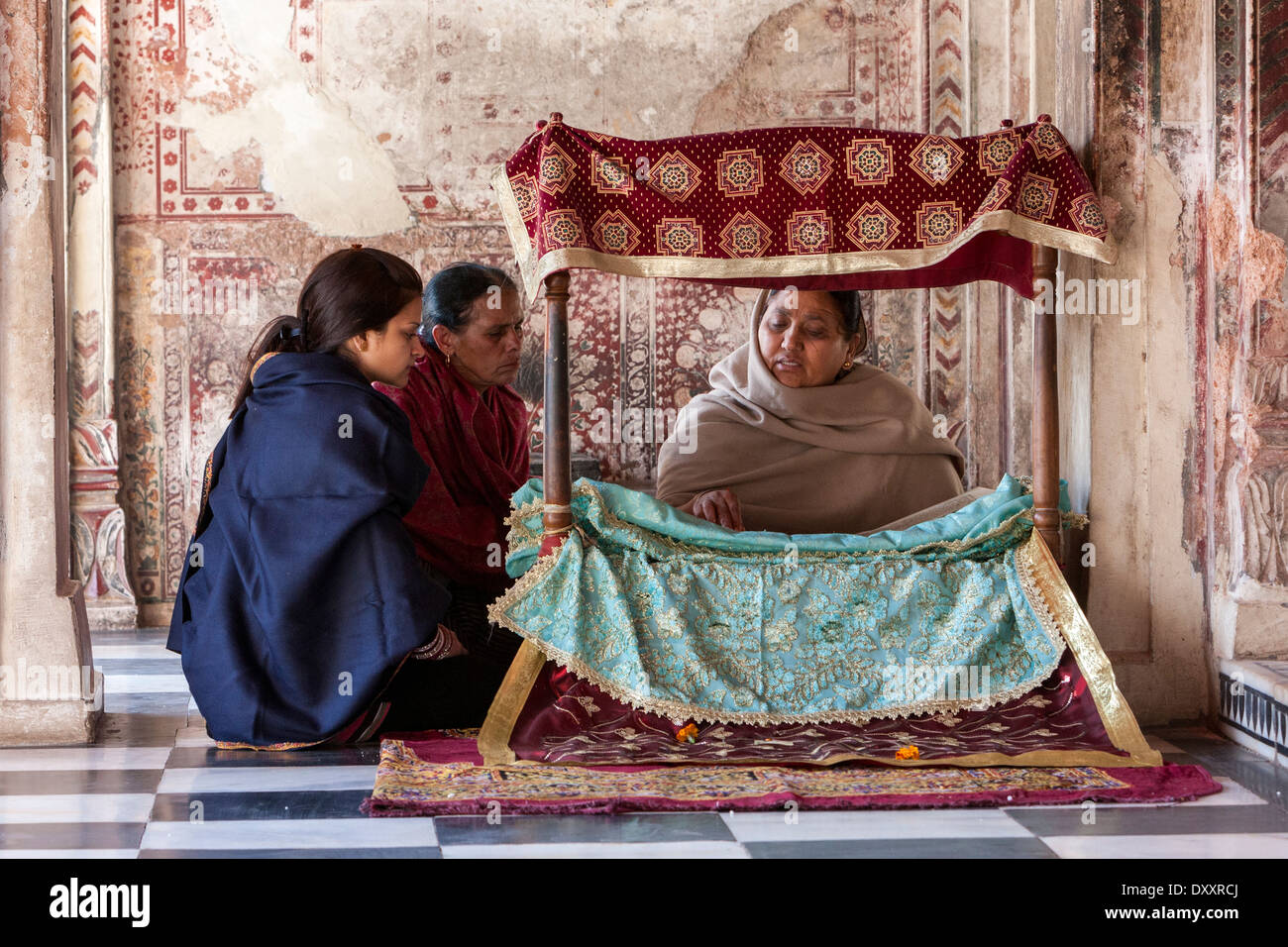 L'Inde, Dehradun. Femme lisant la Sainte Écriture à deux les visiteurs à l'entrée du sanctuaire intérieur d'un temple sikh. Banque D'Images