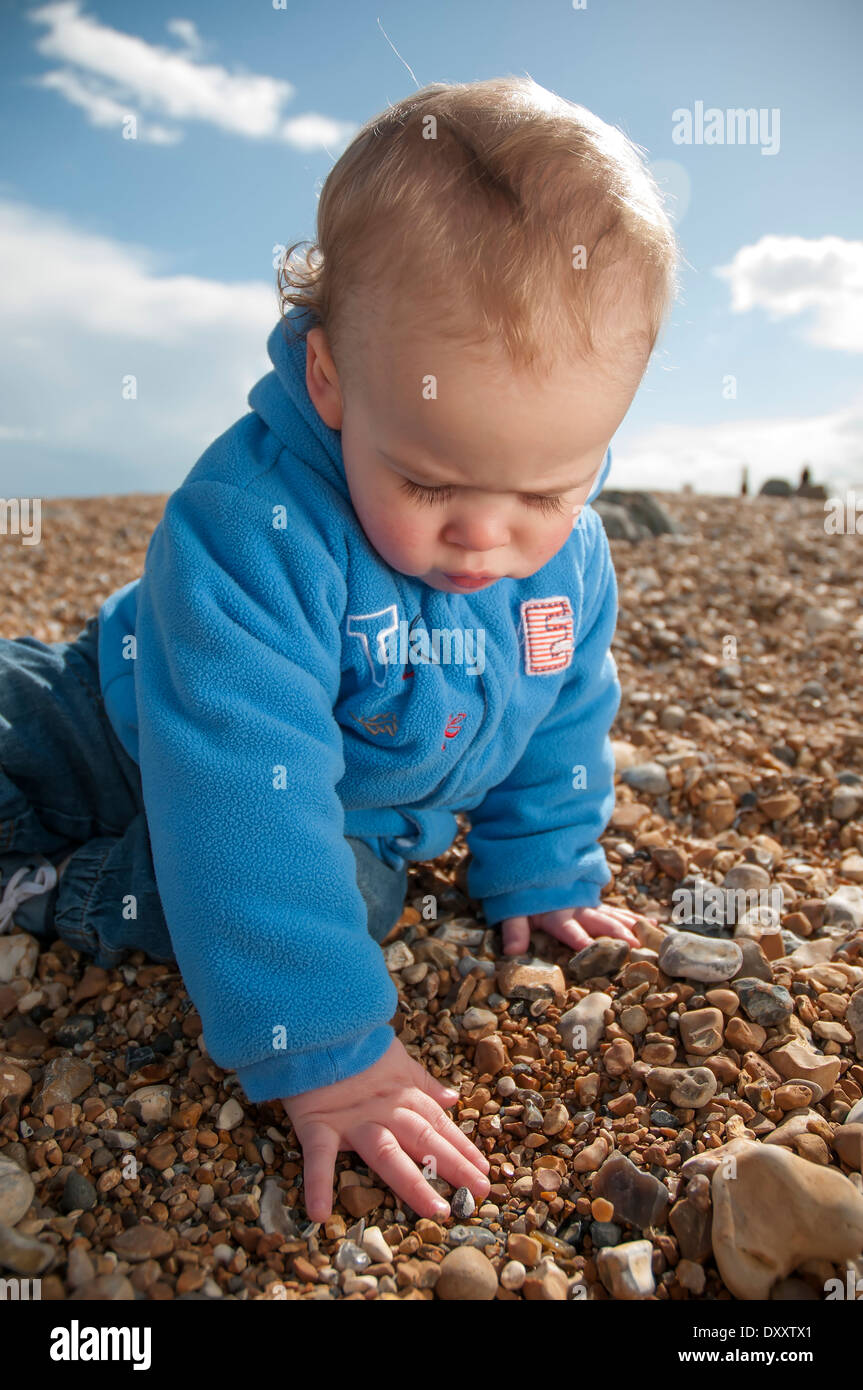 Un mignon petit garçon sur une plage de galets Banque D'Images