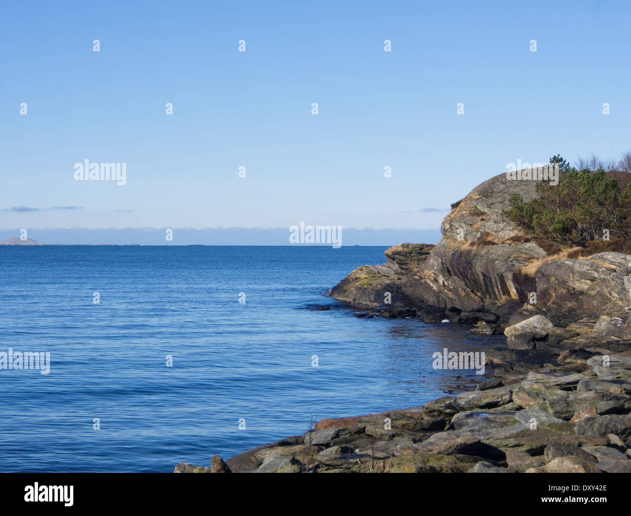 Ciel bleu, mer et rochers, mer calme avec de petites vagues sur la côte de la mer du Nord de la Norvège Banque D'Images