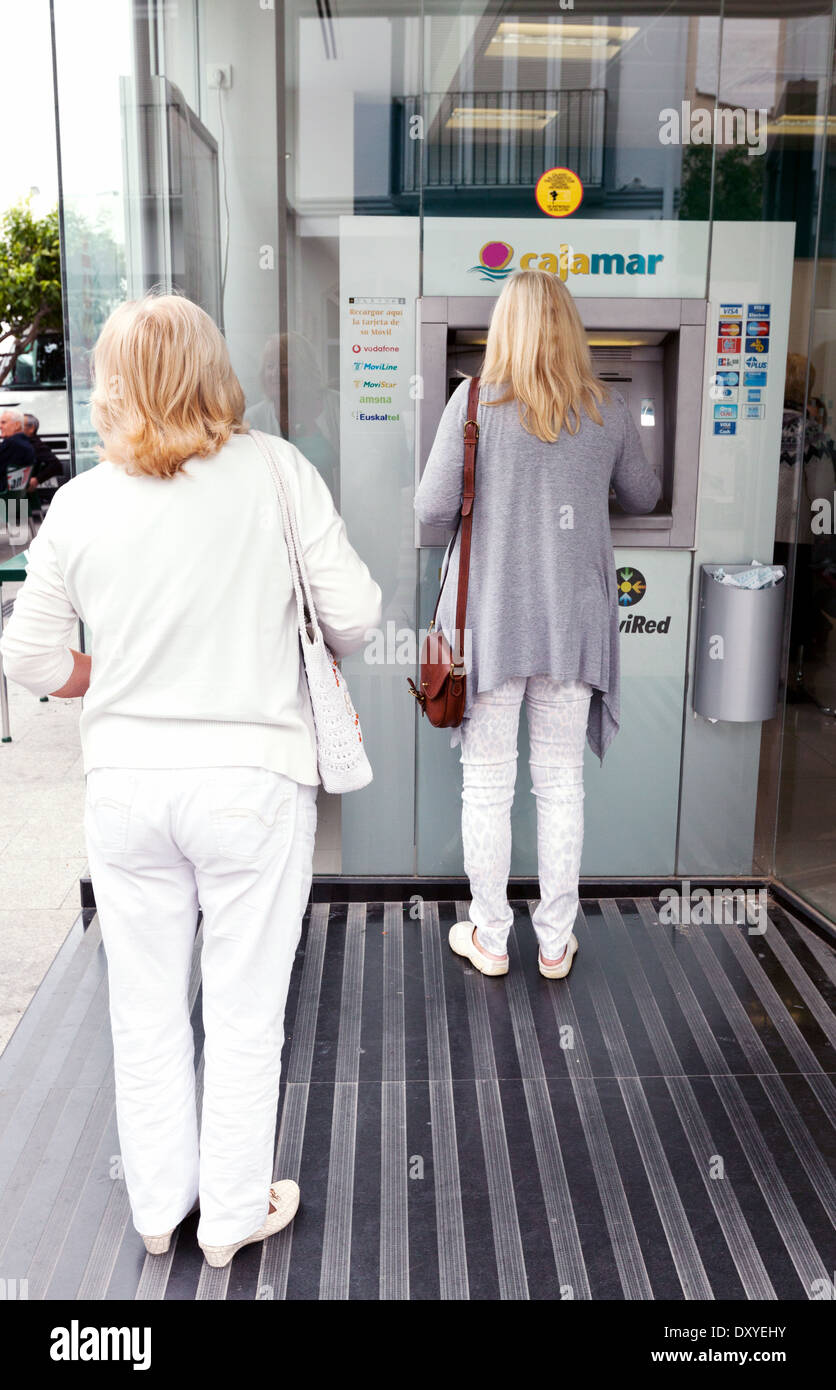 Deux femmes à l'aide d'un guichet automatique bancaire Cajamar cash machine, Turre, Almeria, Andalousie Espagne Europe Banque D'Images