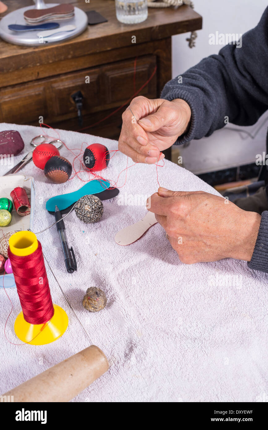 Image main d'hommes experts boules pelote couture, équipements sportifs traditionnels méditerranéens Banque D'Images