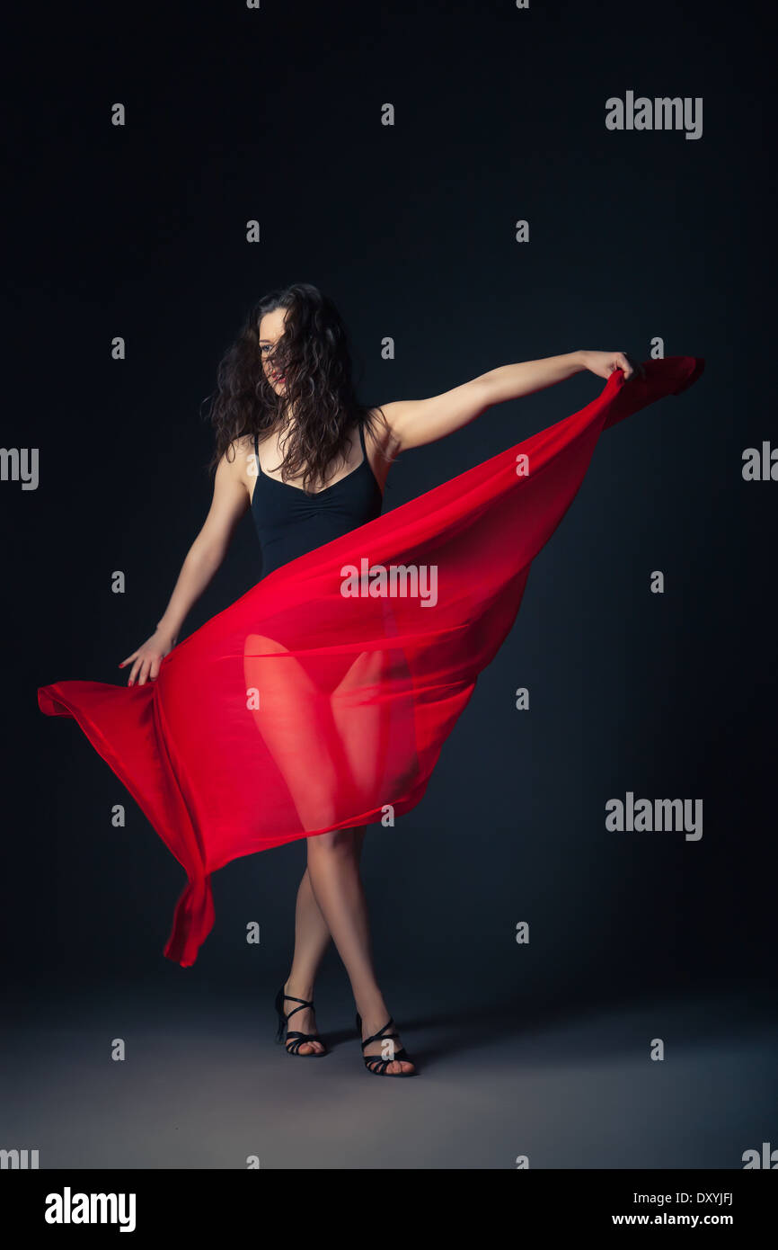 Danseuse de style moderne avec un tissu rouge qui pose sur un fond gris studio Banque D'Images