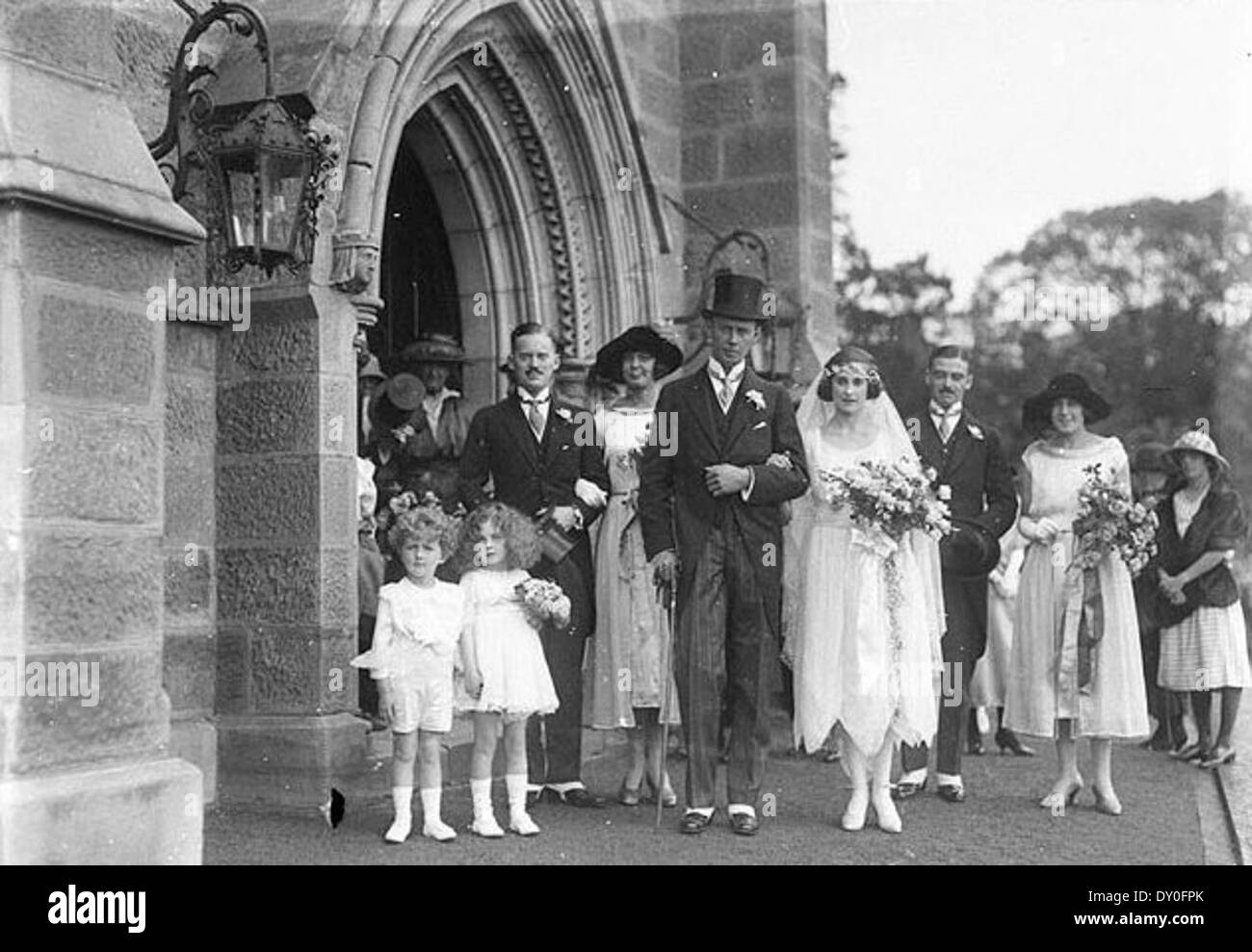 Une photographie de 1922 capturant la fête nuptiale d'Allan Spower et Rosamund Lumsdaine quittant l'église de Mark à Darling point, Sydney. L'image met en valeur la mode et l'architecture de mariage du début du XXe siècle. Banque D'Images
