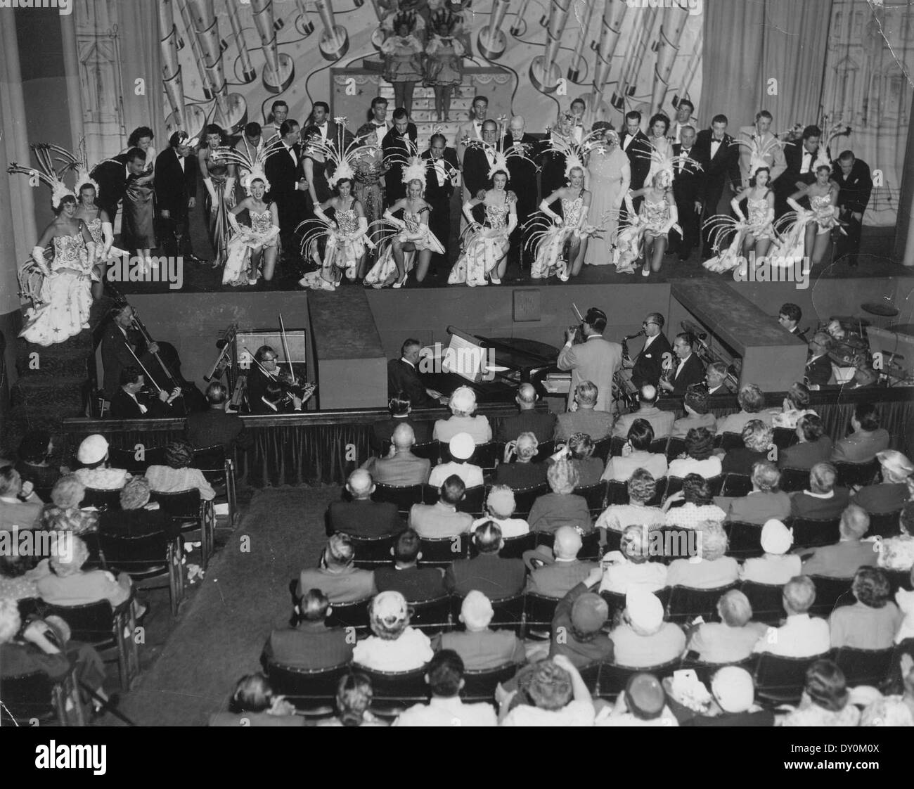 Cette photographie capture la finale de « The Good Old Days » au théâtre Tivoli en 1956-1957. L'image met en valeur la fosse de l'orchestre, le chef d'orchestre et le public, offrant un aperçu de l'atmosphère culturelle vibrante de l'époque. Banque D'Images