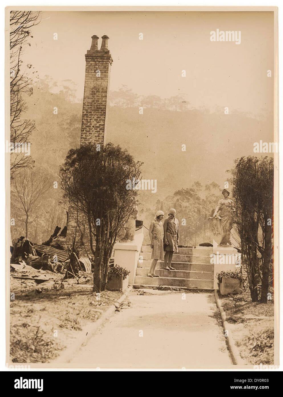 Une photographie de Sam Hood des années 1920 montre des femmes parmi les ruines d'une maison suite à un feu de brousse, dépeignant les conséquences d'une telle catastrophe en Australie. Banque D'Images