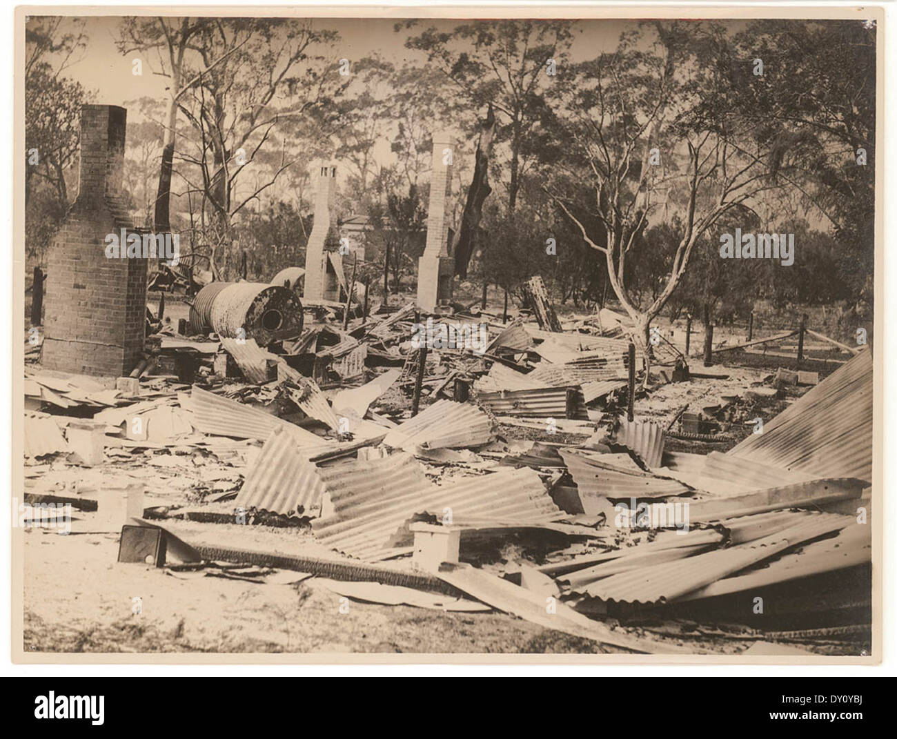Cette photographie des années 1920 de Sam Hood montre les effets dévastateurs d'un feu de brousse en Nouvelle-Galles du Sud, avec une maison complètement détruite par les flammes. L'image reflète les dommages étendus causés par les incendies de cette époque. Banque D'Images