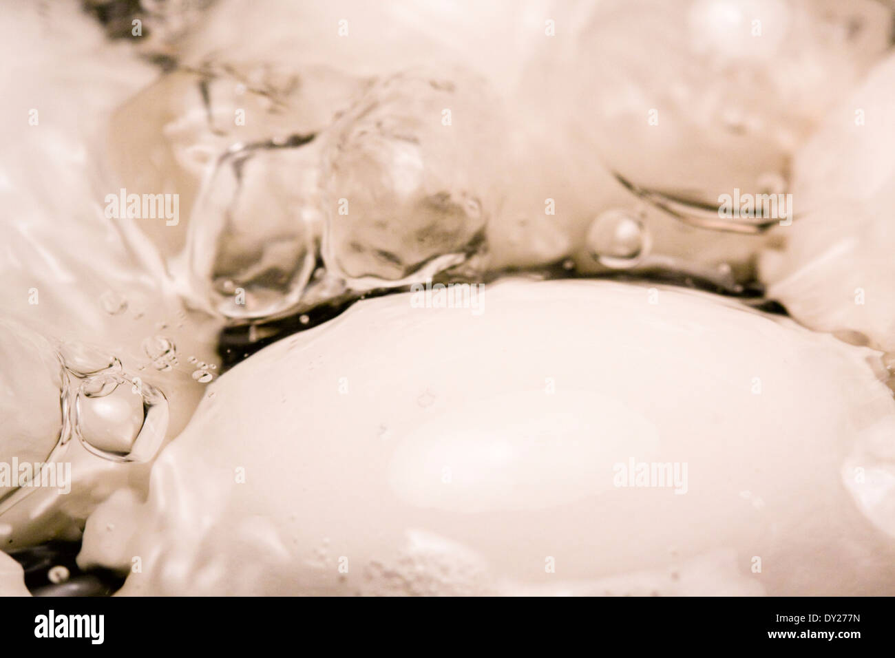 Des bulles apparaissent à la surface de l'eau bouillante comme quatre oeufs blancs sont cuits dans un pot Banque D'Images