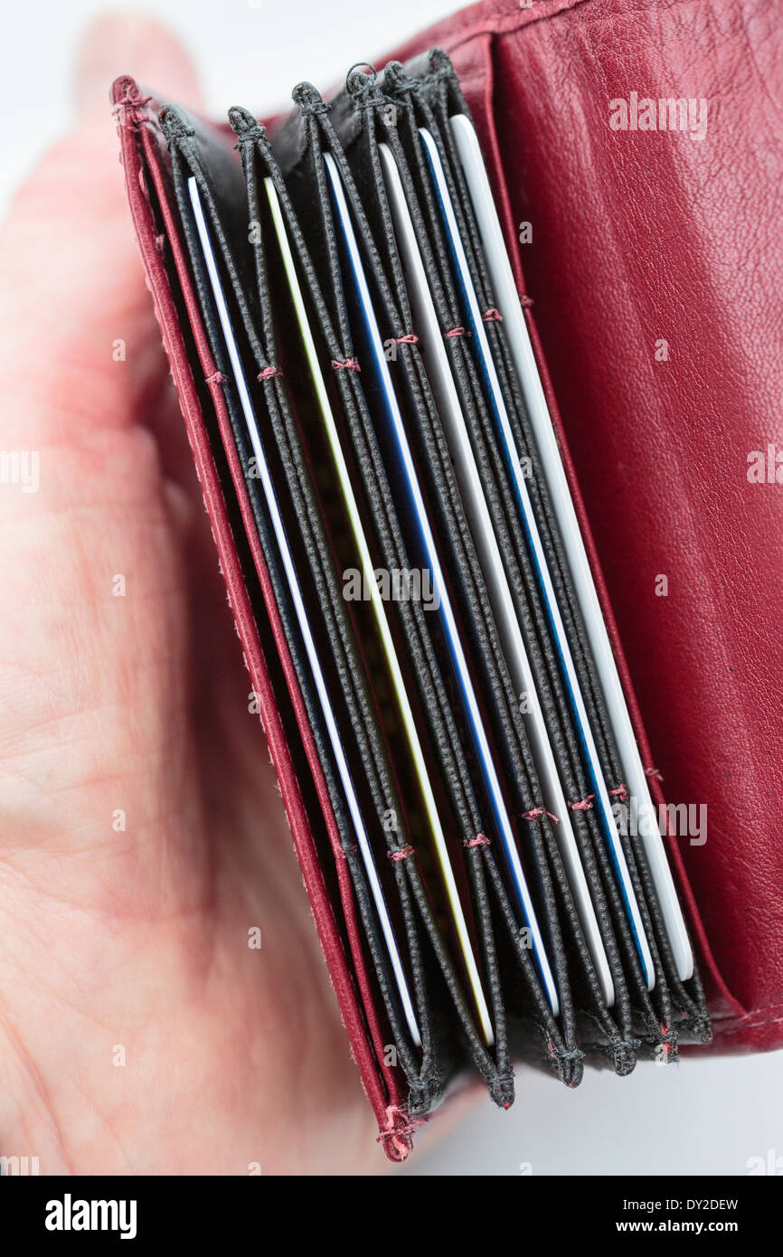 Woman's hand holding red un portefeuille porte-carte avec des fentes contenant des cartes de débit et de crédit de la banque. Angleterre Royaume-uni Grande-Bretagne Banque D'Images