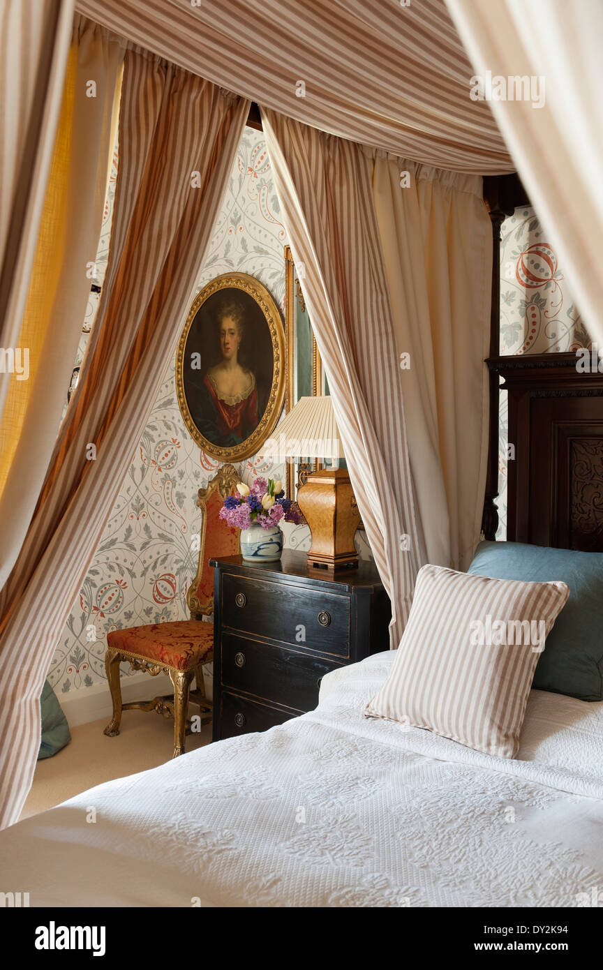 Un lit à baldaquin ornés de coton à rayures Tulsi de Malabar dans chambre avec Chateau Sienne wallpaper par Lewis et du bois Banque D'Images