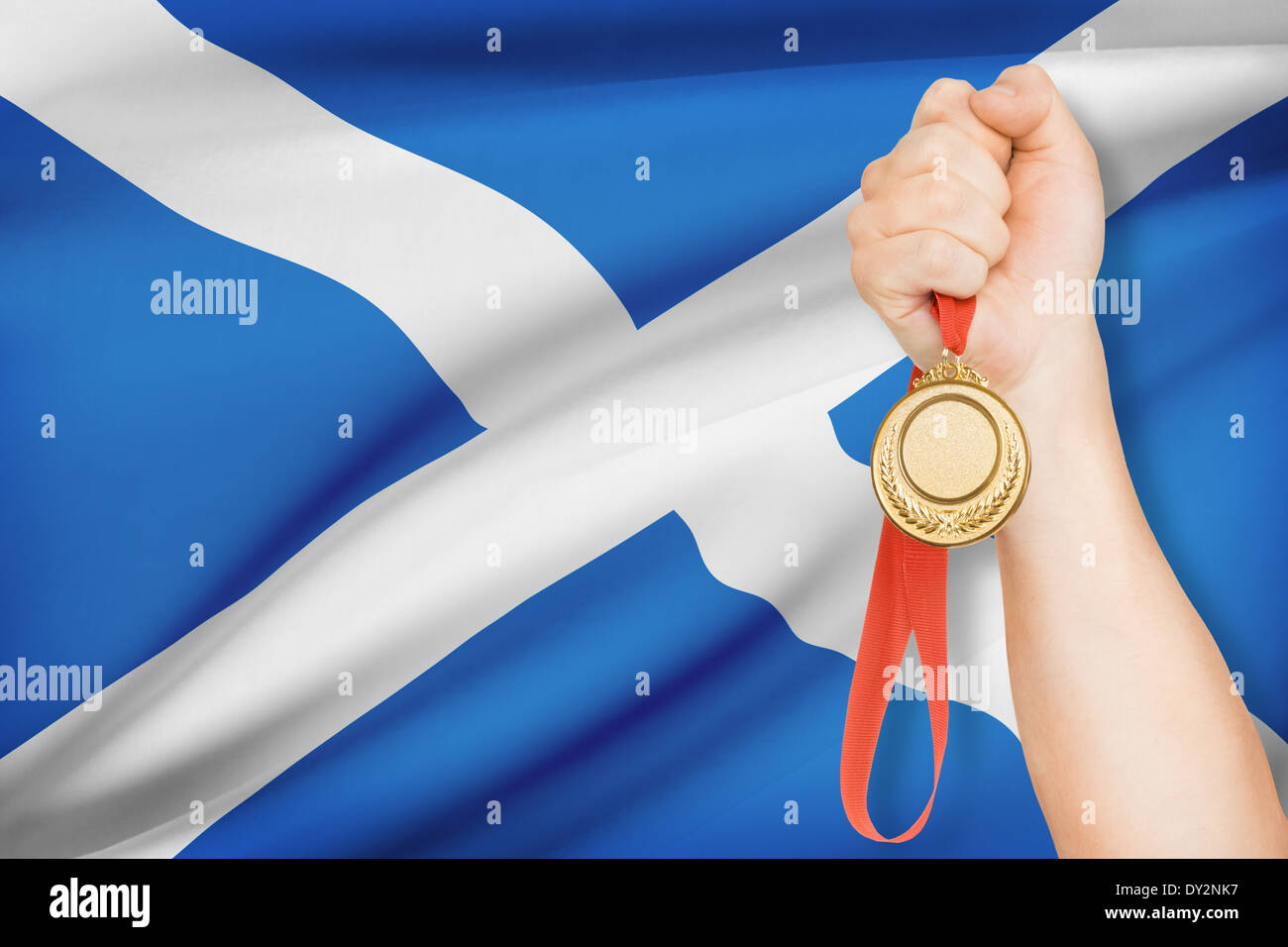 Sportsman holding médaille d'or avec drapeau sur arrière-plan - Ecosse Banque D'Images