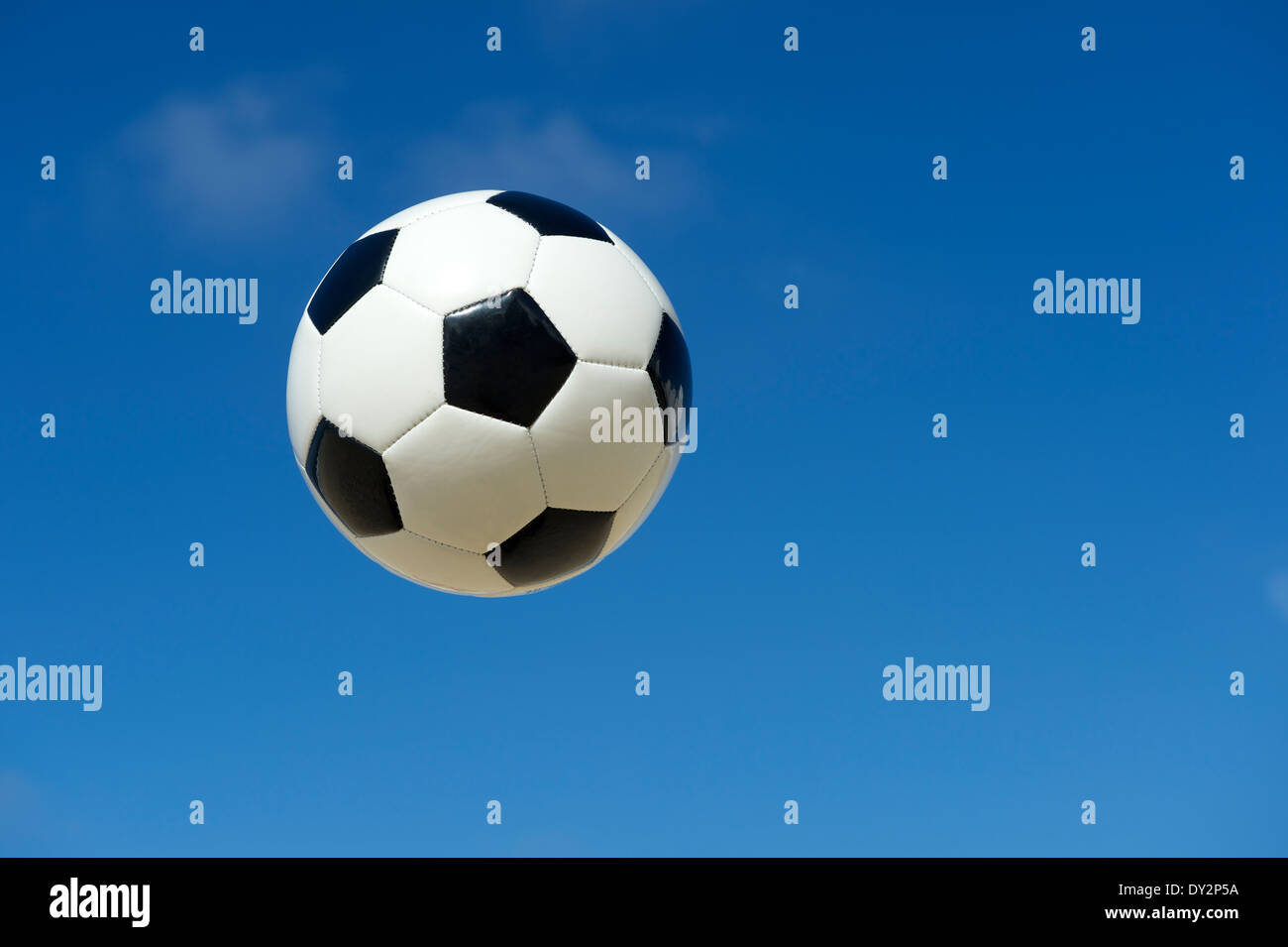 Classique noir et blanc ballon de soccer foot flottant dans un bleu ciel d'été Banque D'Images