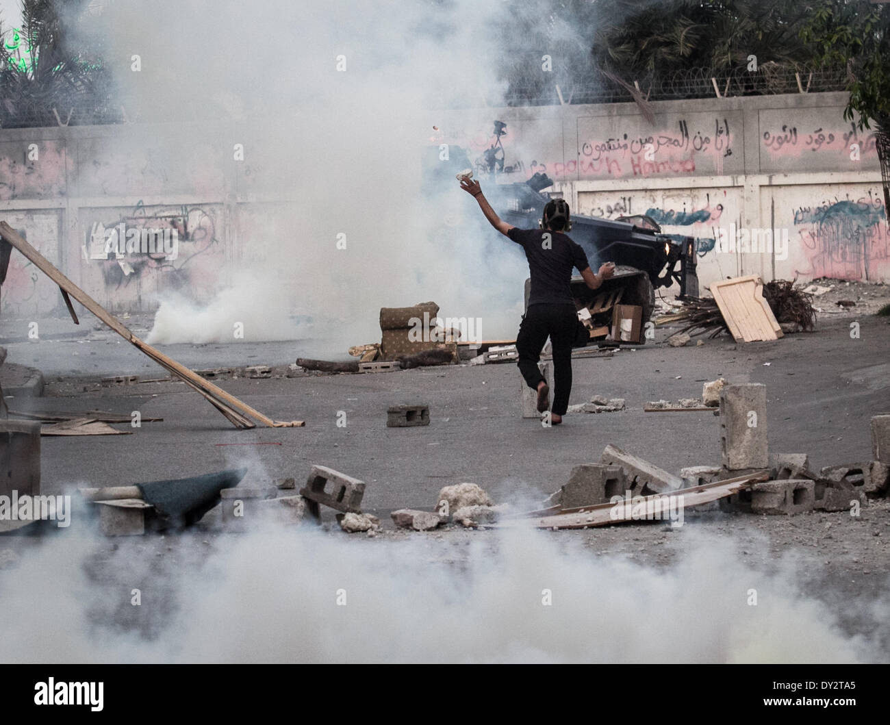 Janosan, Bahreïn. 4ème apr 2014. Manifestant une police incendie qui confronte les gaz lacrymogènes à partir d'un véhicule blindé. Le Centre pour les droits de l'homme a appelé au boycottage de l'île du grand prix de Formule 1 qui aura lieu ce week-end, de sporadique manifestations anti-gouvernementales se poursuivent dans le pays. © Ahmed Alfardan/NurPhoto ZUMAPRESS.com/Alamy/Live News Banque D'Images