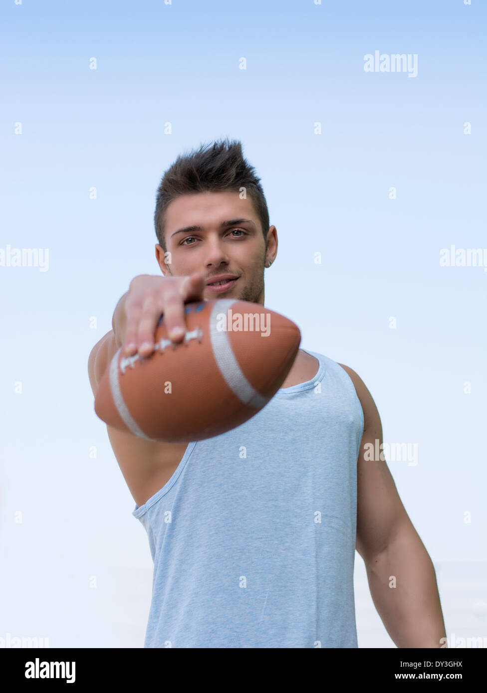 Football américain musculaire avec ballon en main, face à l'appareil photo Banque D'Images