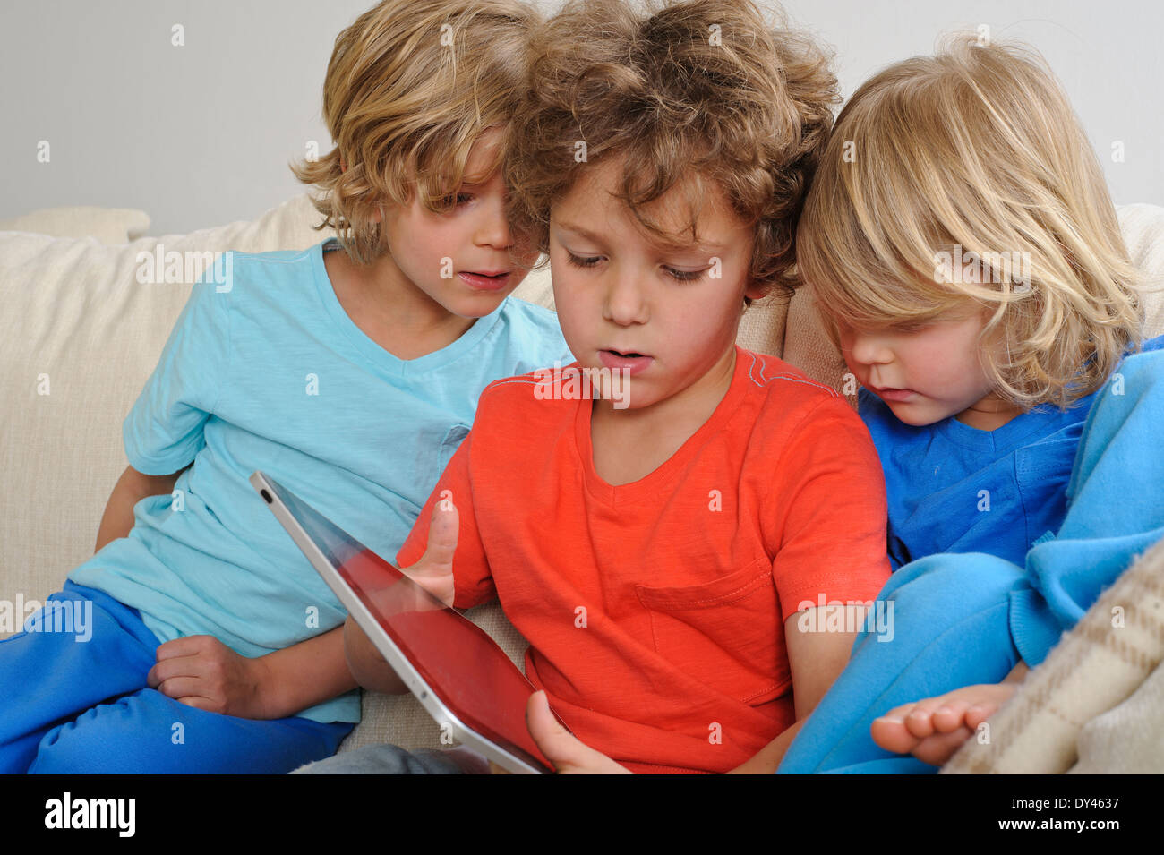 Un 8-9 ans est de jouer à un jeu sur un écran tactile Tablet. Ses jeunes frères sont à regarder attentivement chaque mouvement Banque D'Images