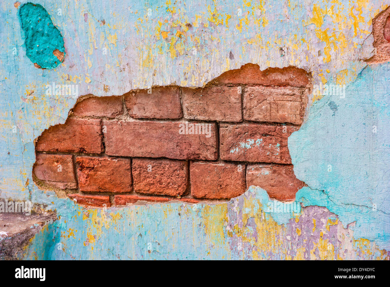 Plâtre peint coloré chipping off un mur de briques Banque D'Images
