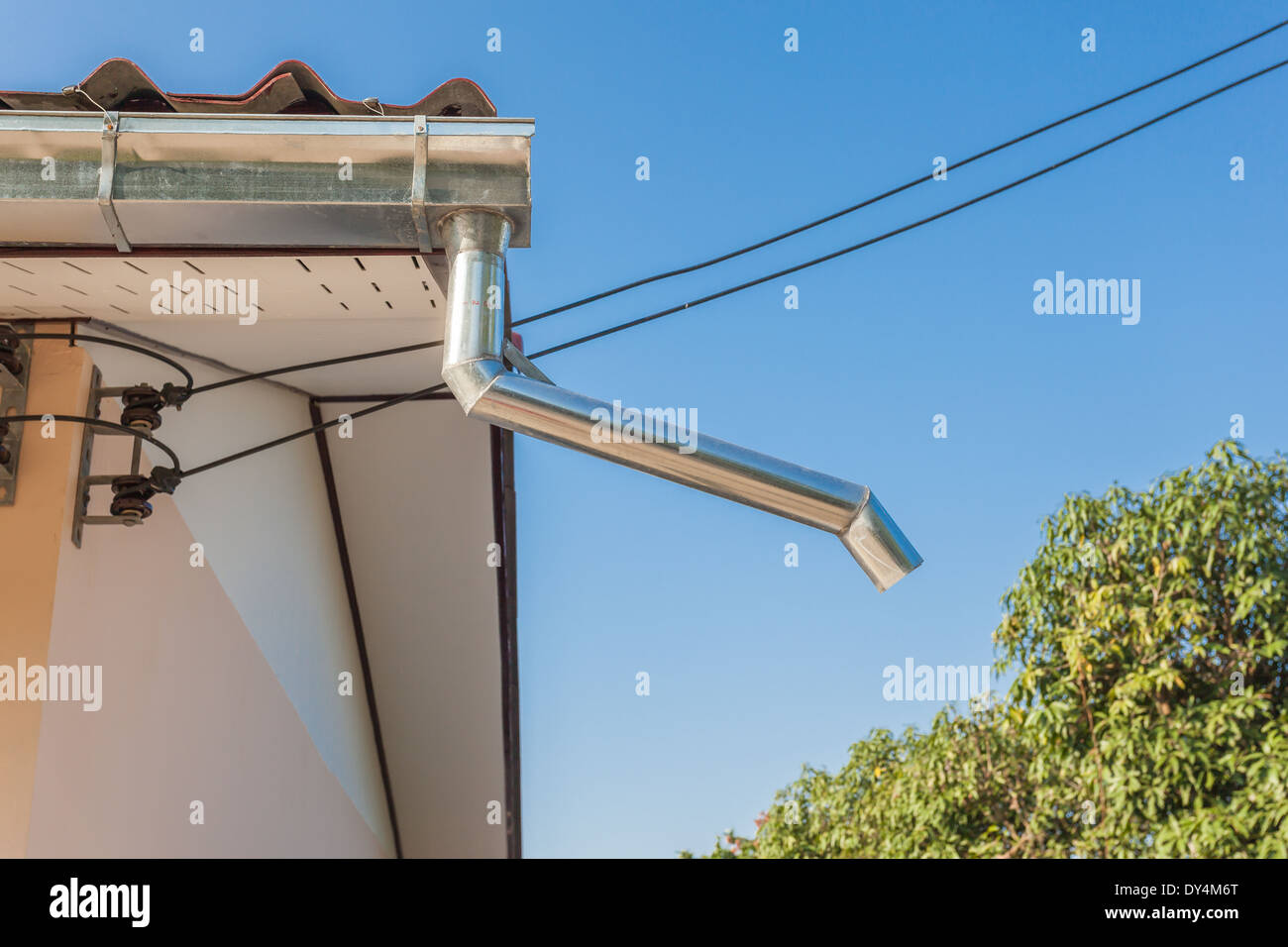 Sur le toit se trouve une gouttière à côté d'un arbre Banque D'Images