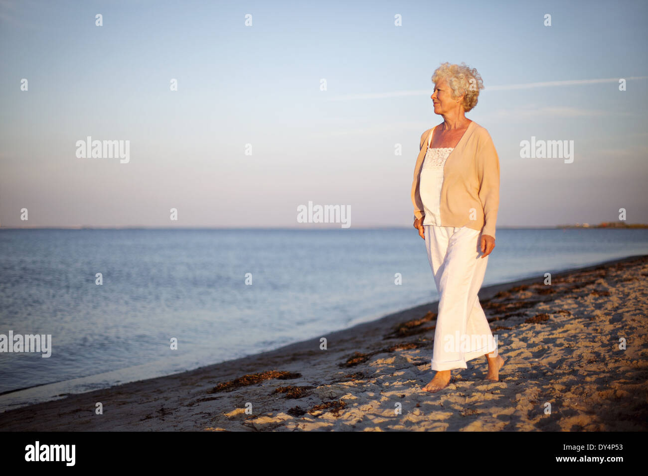 Portrait of a young woman walking sur la plage face à la mer. Vieille dame détendue sur la plage avec l'exemplaire de l'espace. Banque D'Images