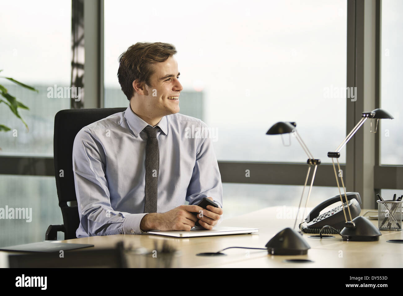 Young businessman sitting at desk in office Photo Stock - Alamy