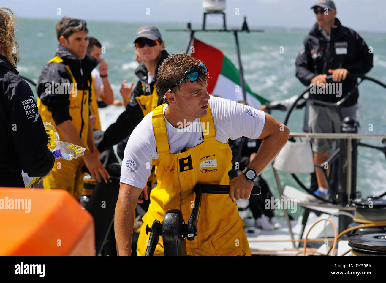 Treuil d'équipage à bord de meulage ocean racing yacht, avec le skipper sur la roue derrière Banque D'Images