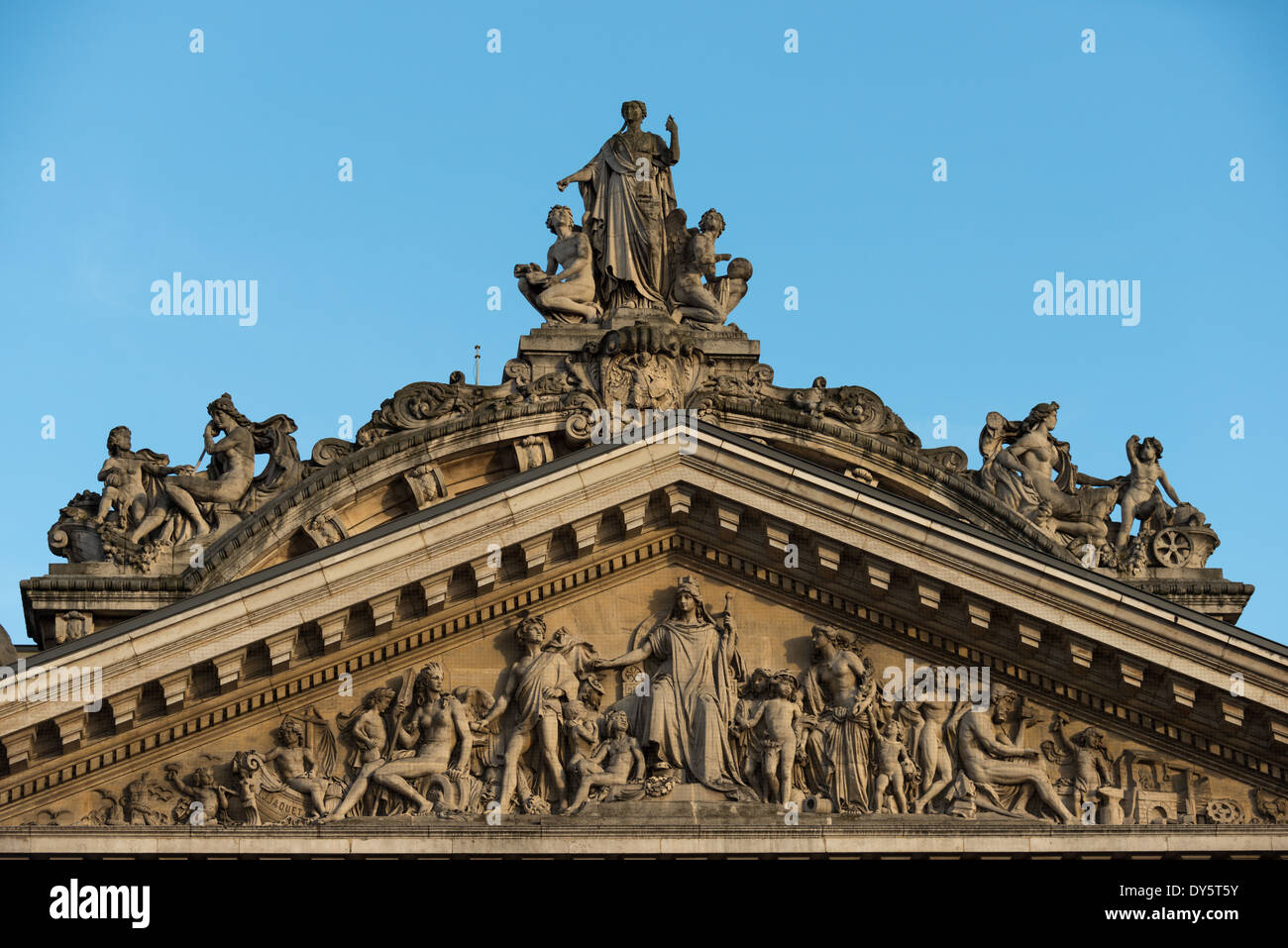 Sculpture du fronton de la Bourse de Bruxelles // BRUXELLES, Belgique — un fronton orné orne le bâtiment de la Bourse de Bruxelles, illustrant la décoration architecturale élaborée de la période de construction de 1868-1873. Cet élément sculptural combine les styles néo-Renaissance et second Empire, mettant en vedette des œuvres d'artistes de renom tels que les frères Jacquet, Guillaume de Groot, Albert-Ernest Carrier-Belleuse et Auguste Rodin. Le fronton illustre l'ornementation architecturale sophistiquée des bâtiments publics belges du XIXe siècle. Banque D'Images