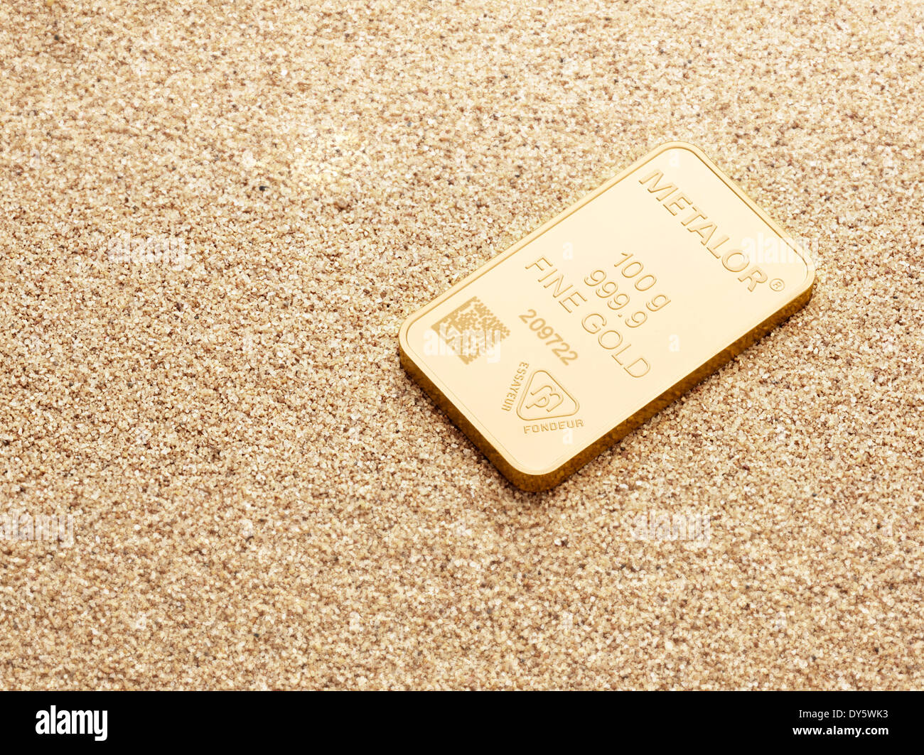100g barre d'or sur fond de sable Banque D'Images